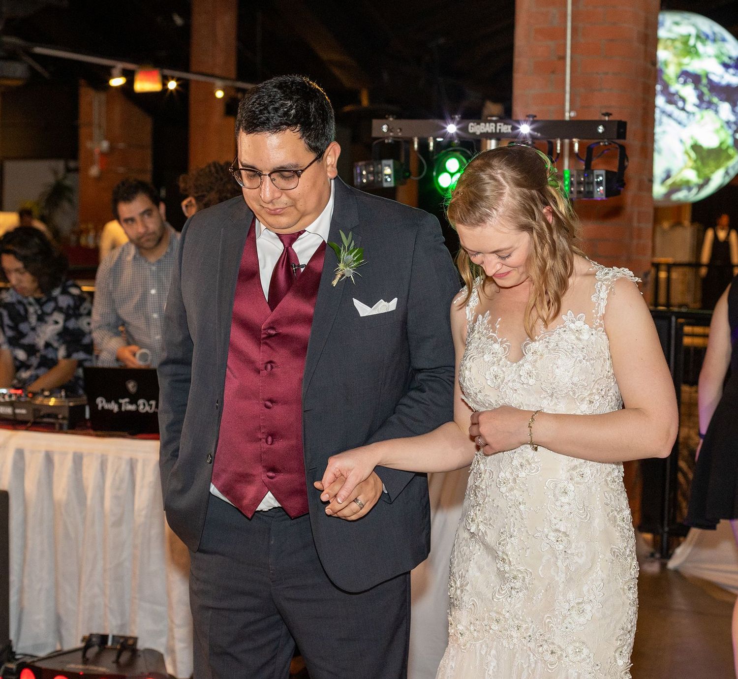 Bride and groom share a dance at their wedding reception, with DJ equipment visible in the background.