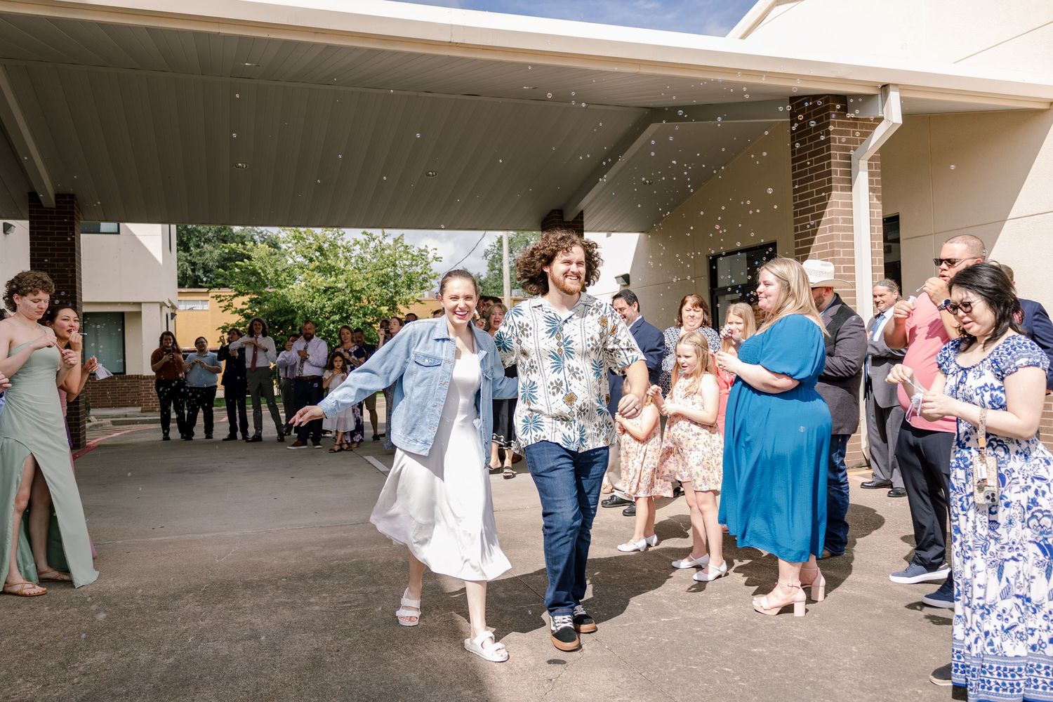 Guests form an aisle outside as they celebrate the couple's departure.