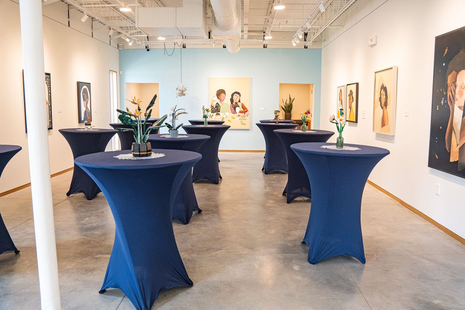 Elegant wedding reception venue with navy blue cocktail tables in an art gallery.