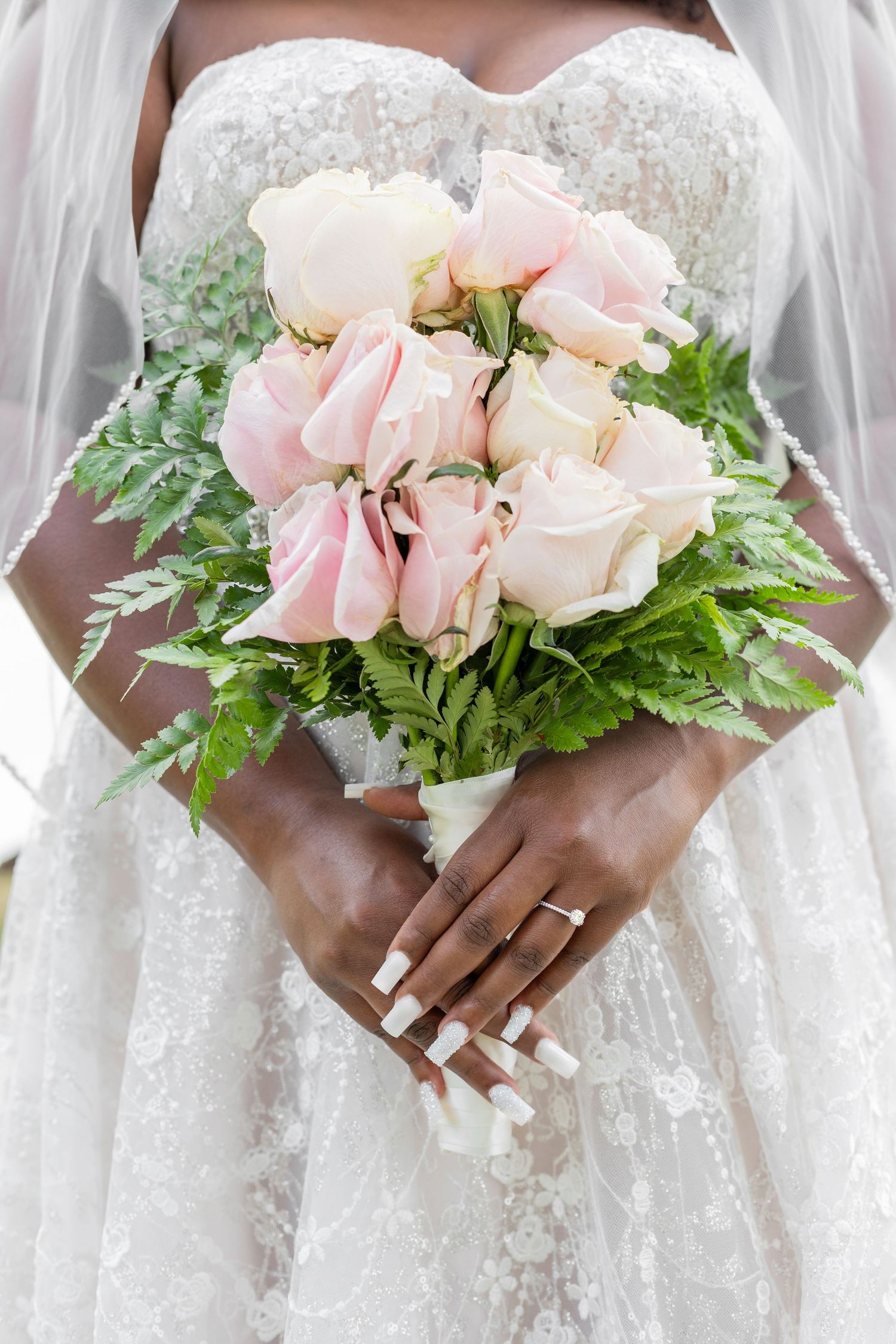 Elegant bridal bouquet of pink roses with white dress details.