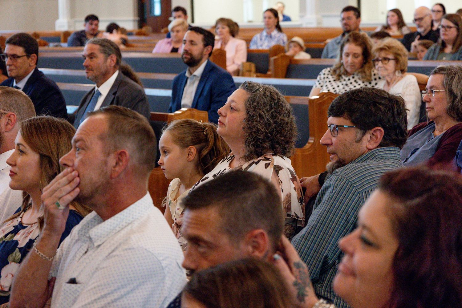 Wedding guests seated in church pews watch the ceremony.