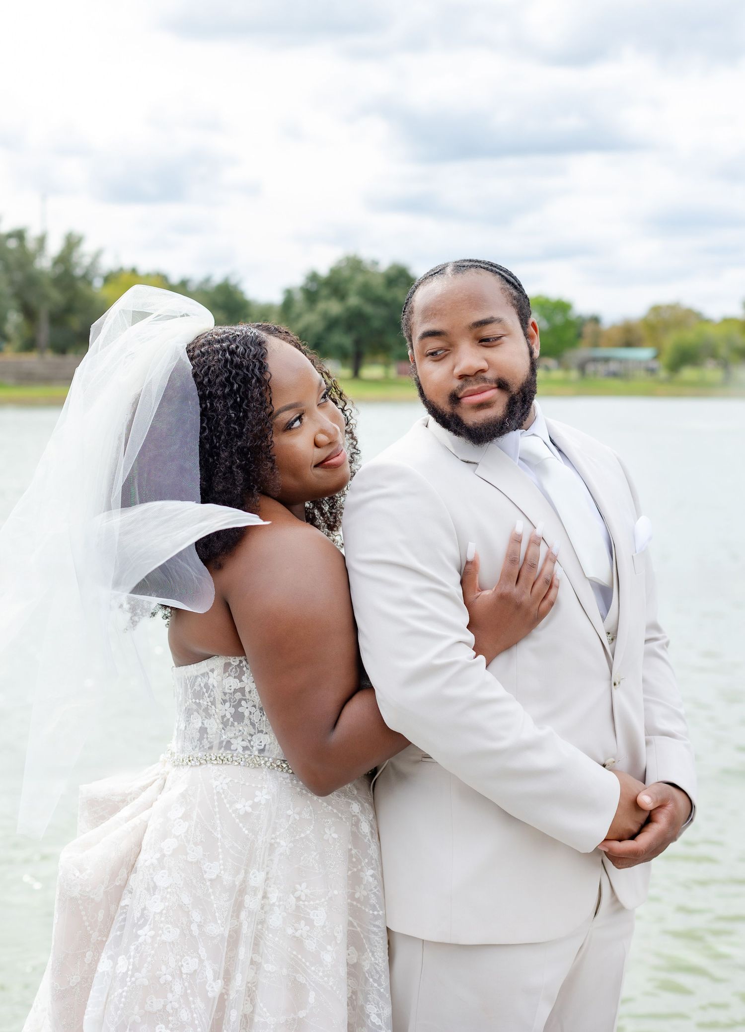 Joyful wedding couple sharing laughs on waterfront deck.
