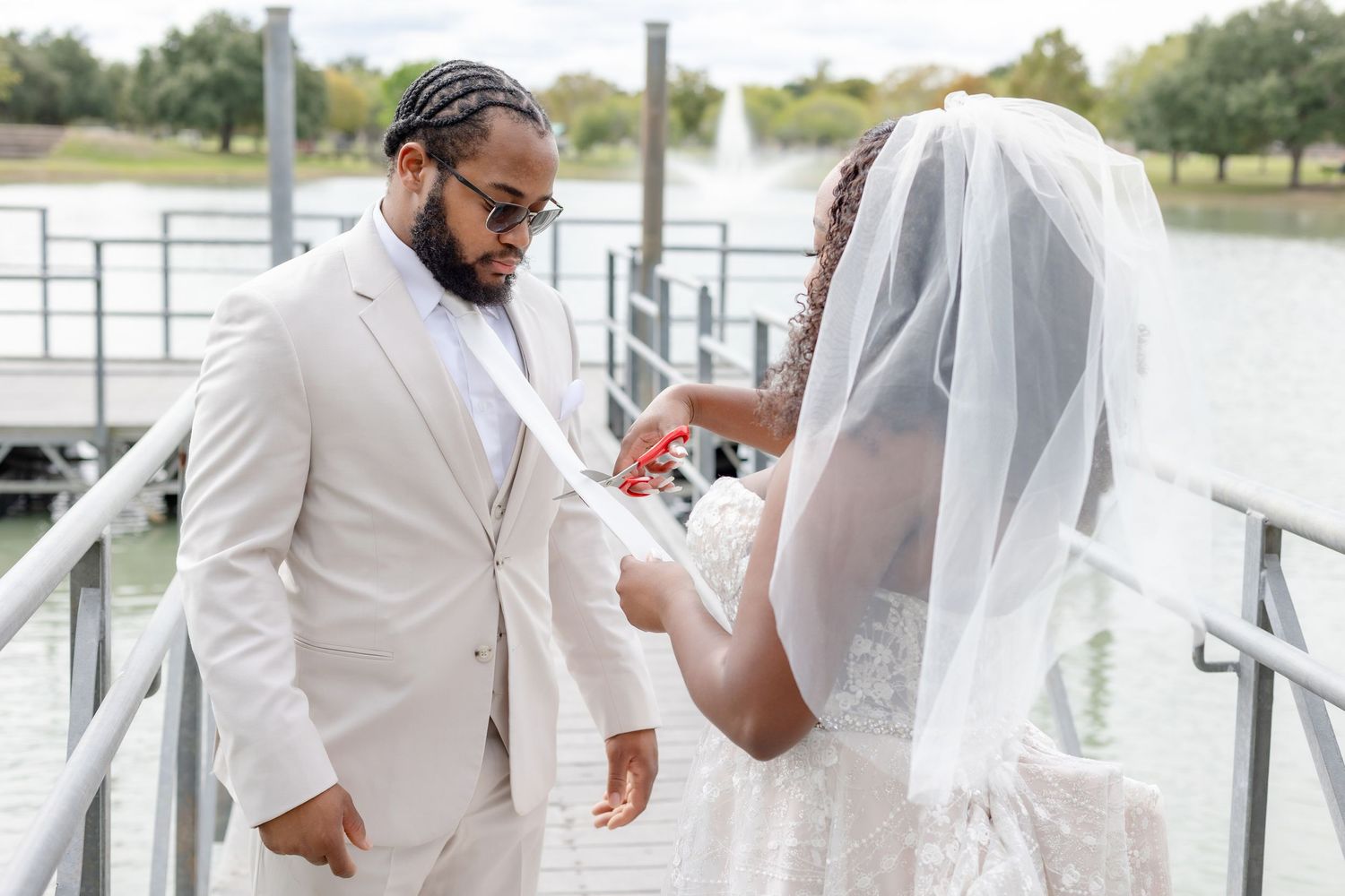 Wedding couple walking along waterfront dock in elegant white attire.