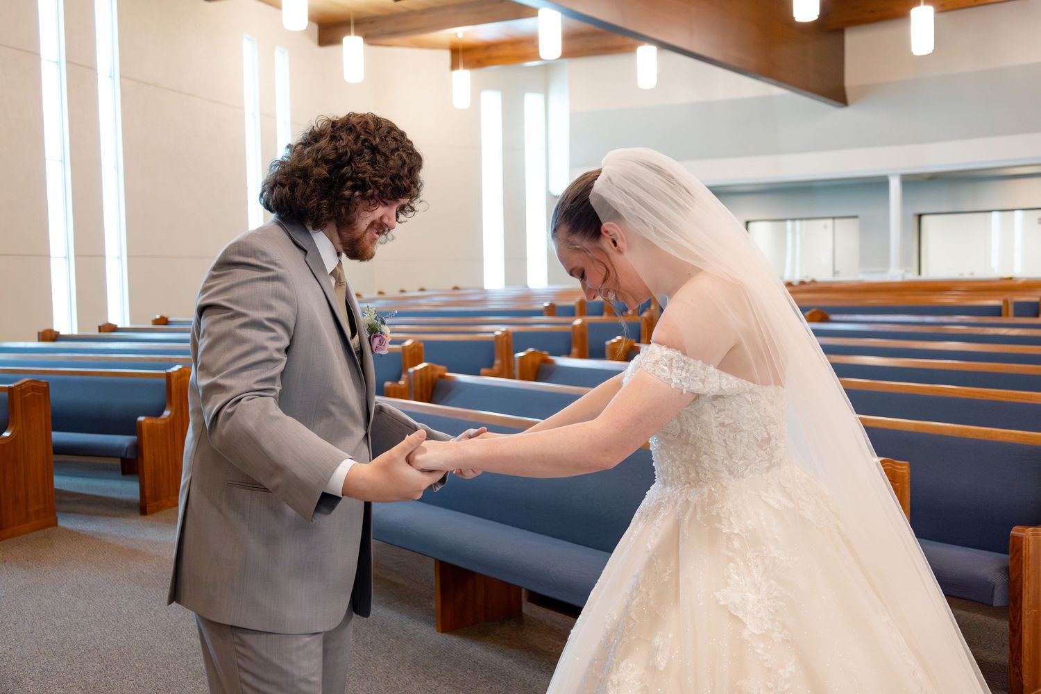 Happy couple interacts playfully in a modern church sanctuary with blue pews and wood accents.
