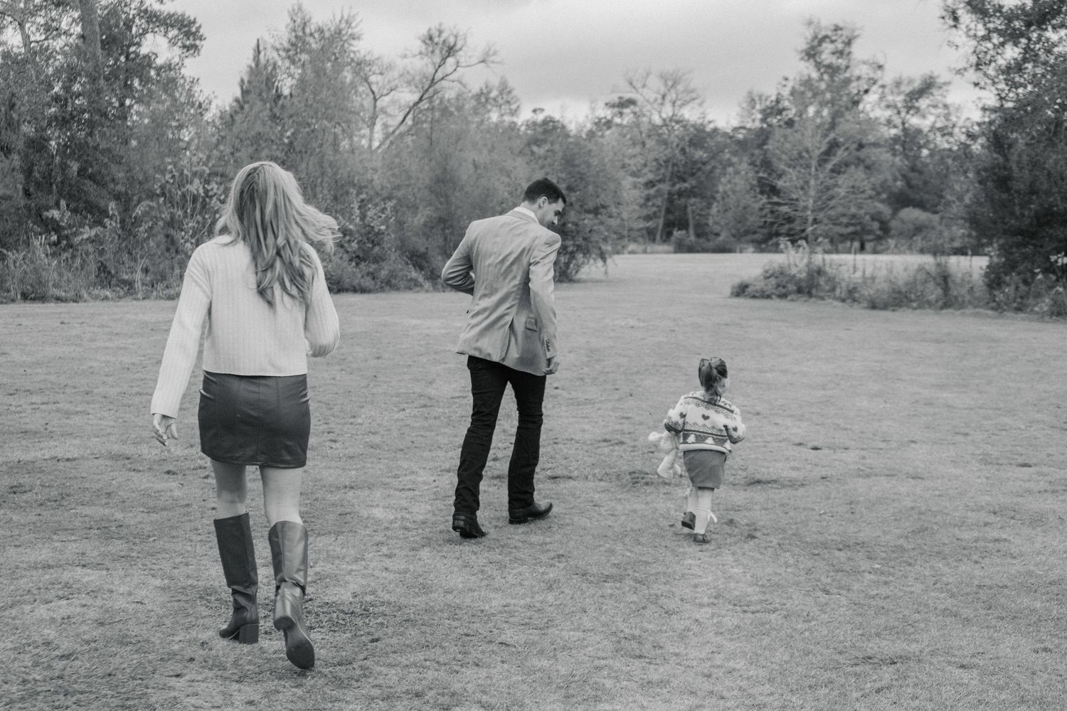 A series of black and white photos showing people walking together through a grassy field on a sunny day.