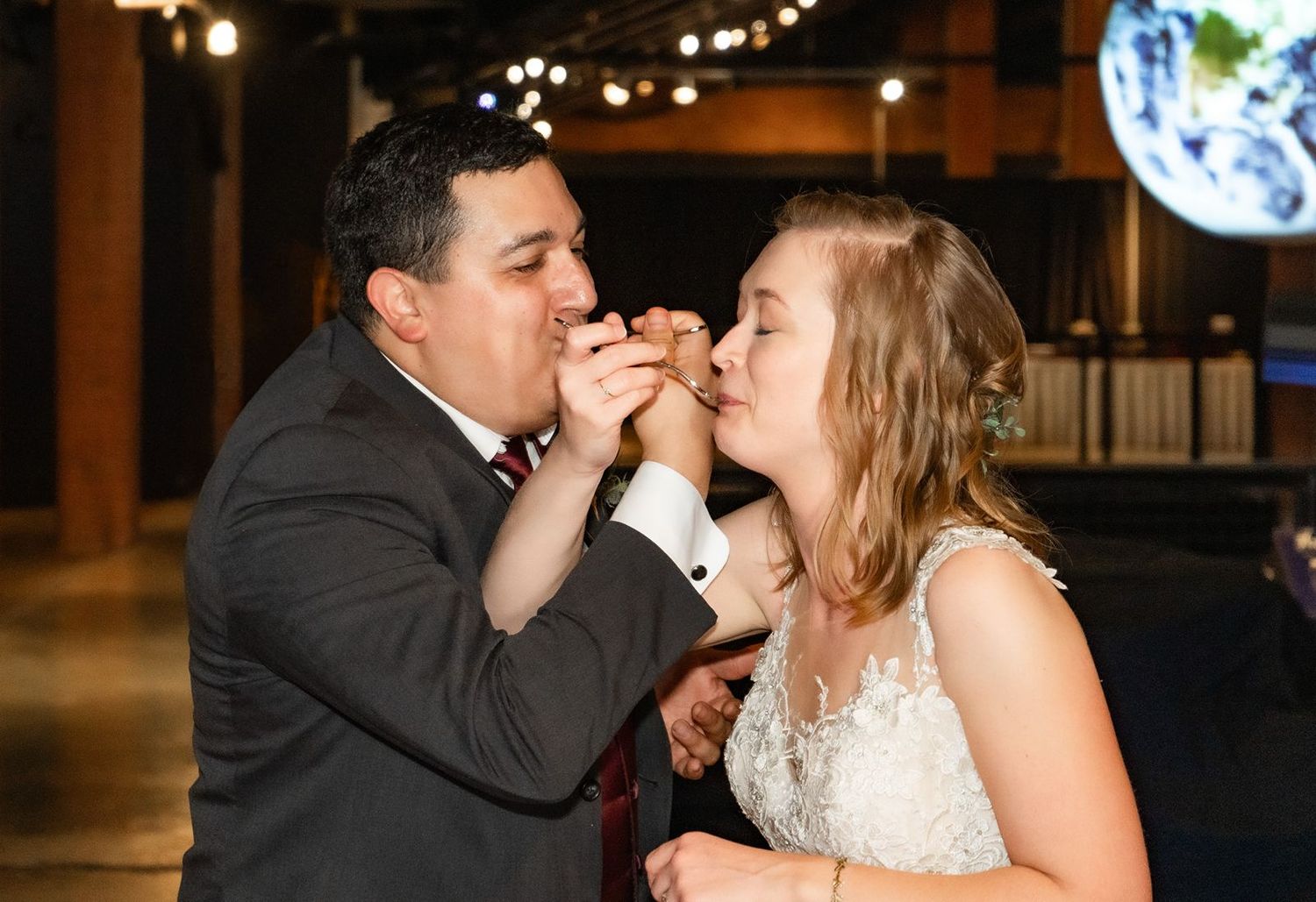 Bride and groom sharing wedding cake during reception ceremony.