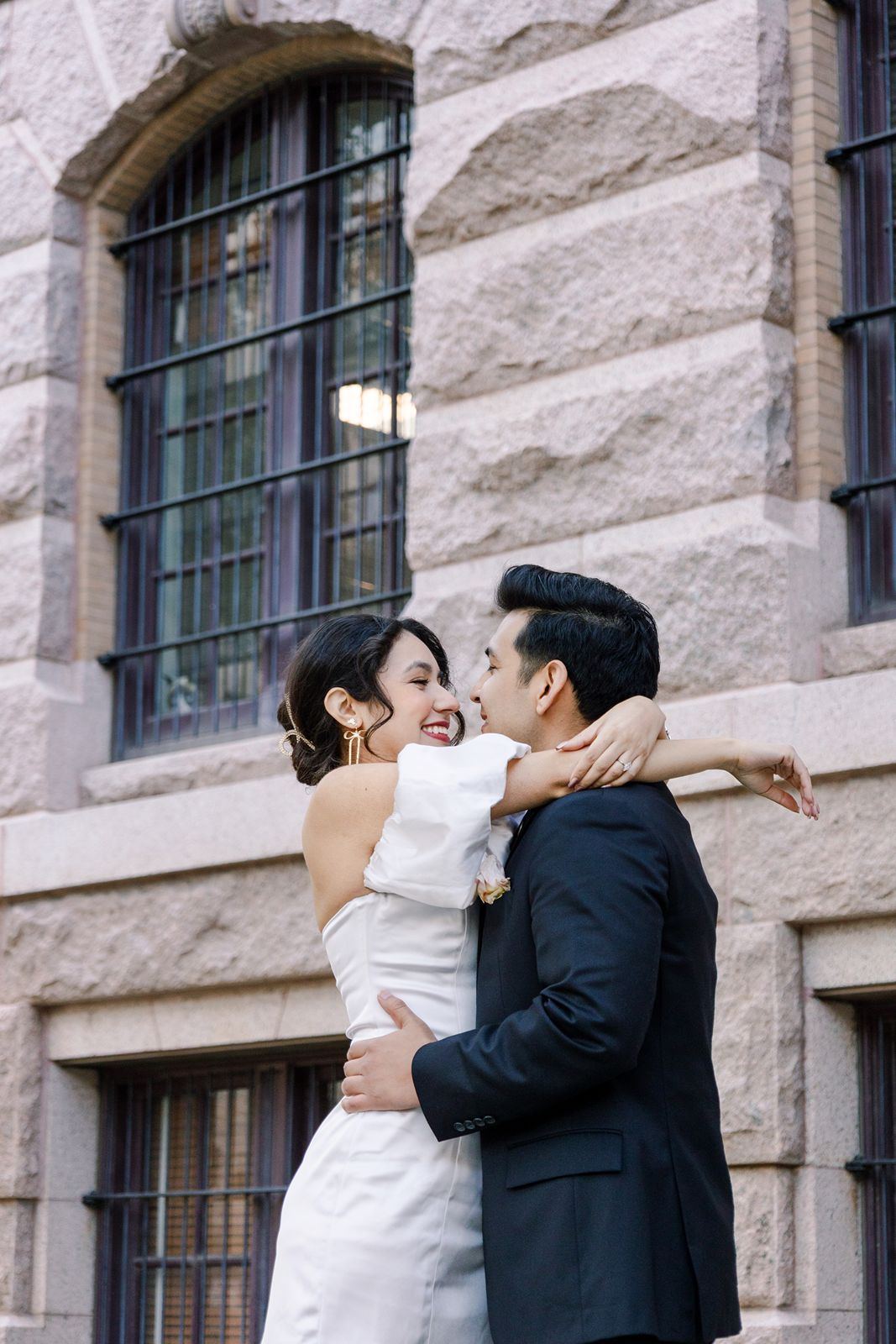 A romantic couple shares a tender kiss against a stone building with arched windows in a series of sequential photos.
