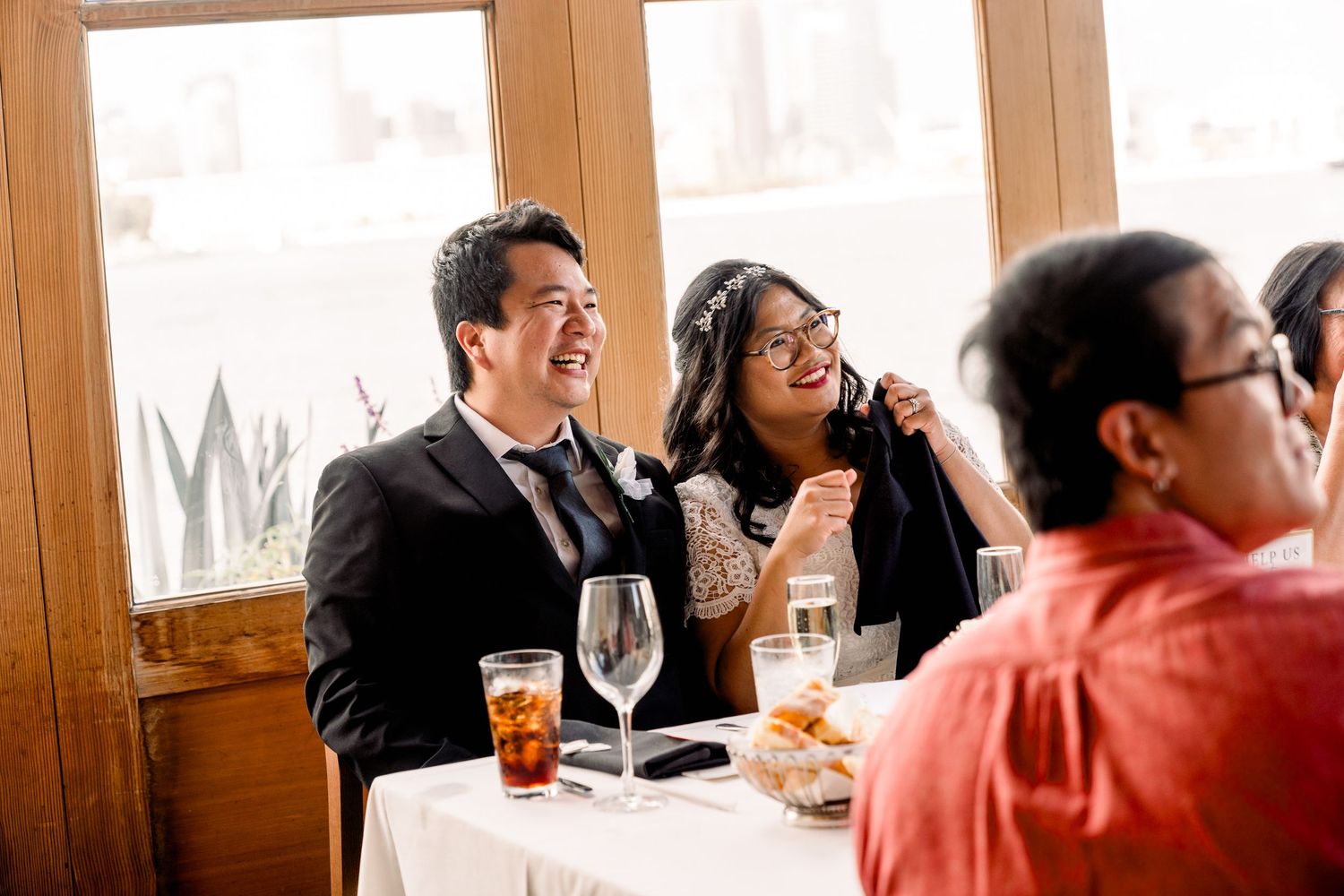 Wedding guests enjoying a reception dinner in a sunlit room.