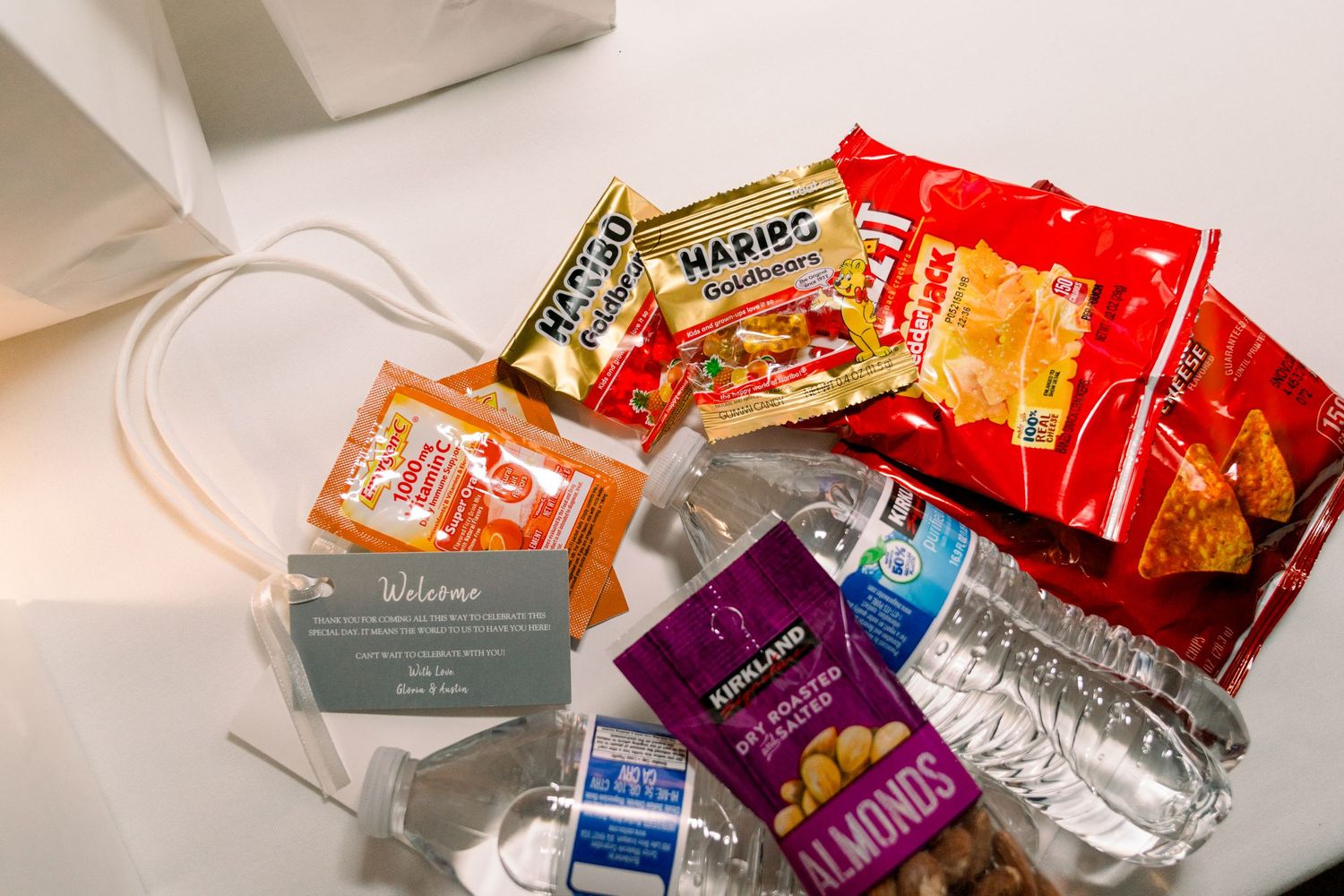 Collection of colorful snack packets and treats in a white gift bag.