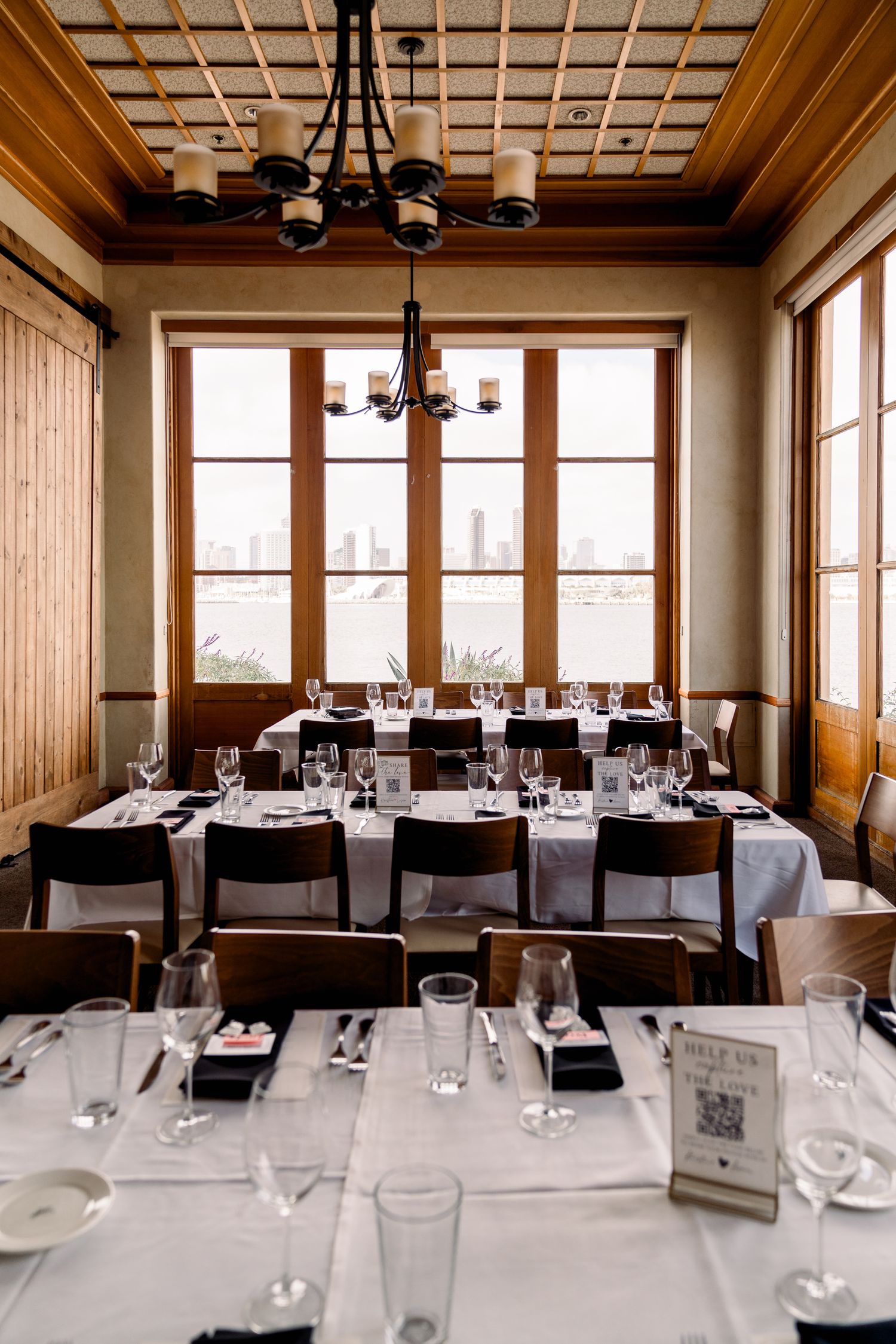 Elegant wedding reception dining room with chandelier, large windows, and tables set with white linens.