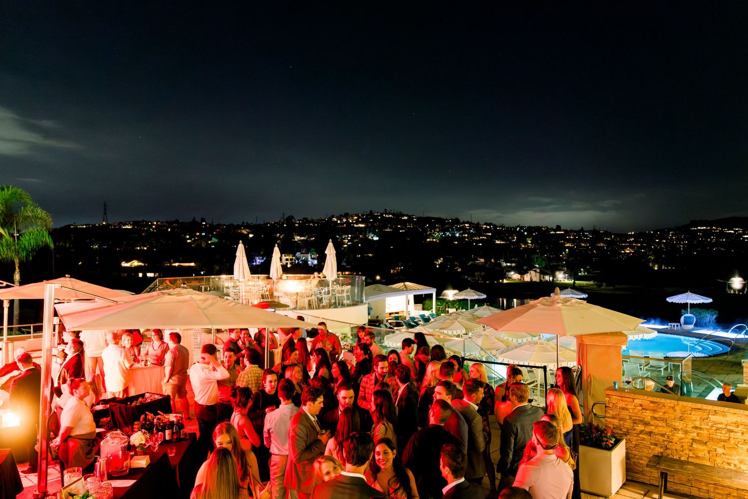 Rooftop party venue at night with crowd gathering under ambient lighting.