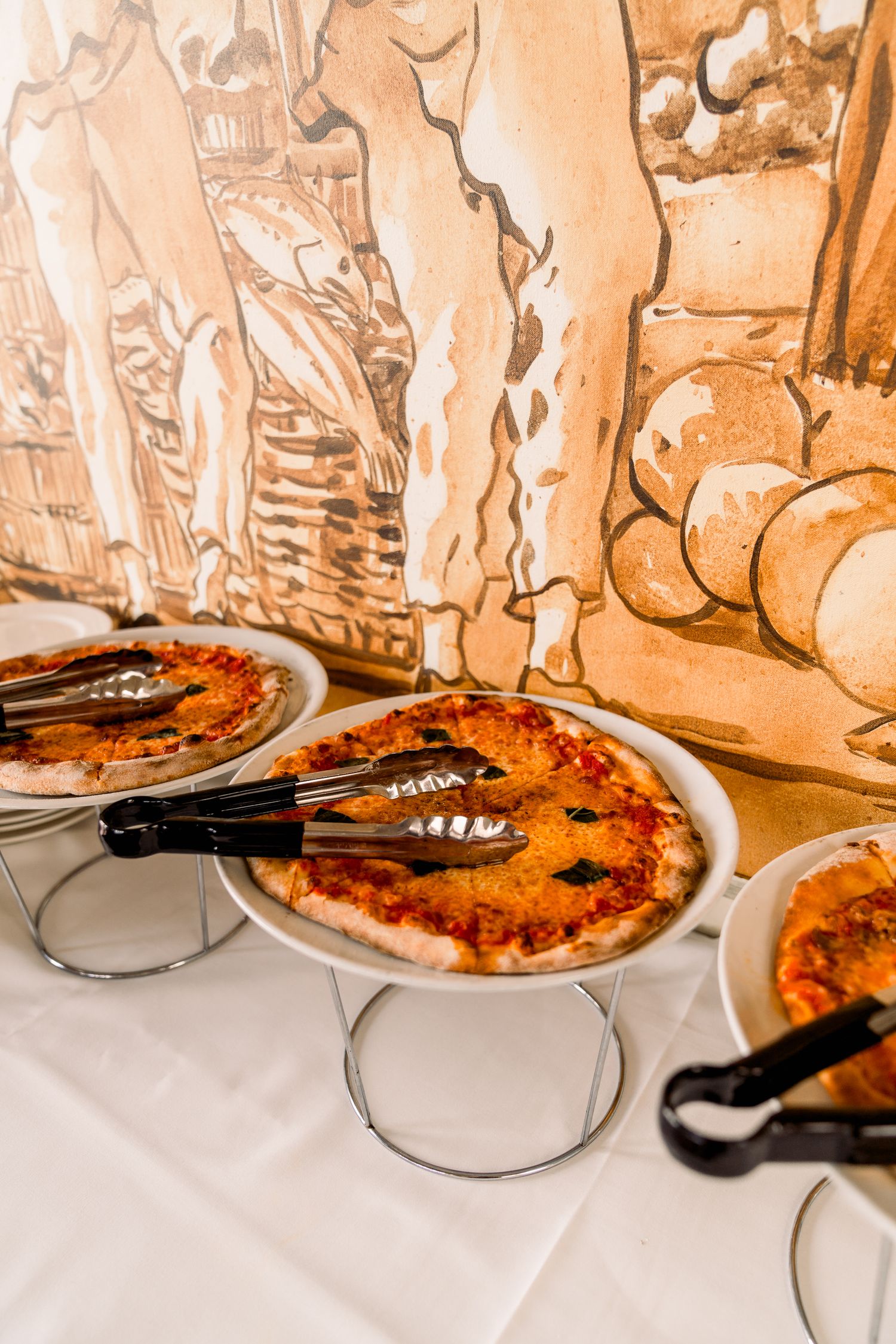 Multiple pizzas served on white plates at an elegant catered event.