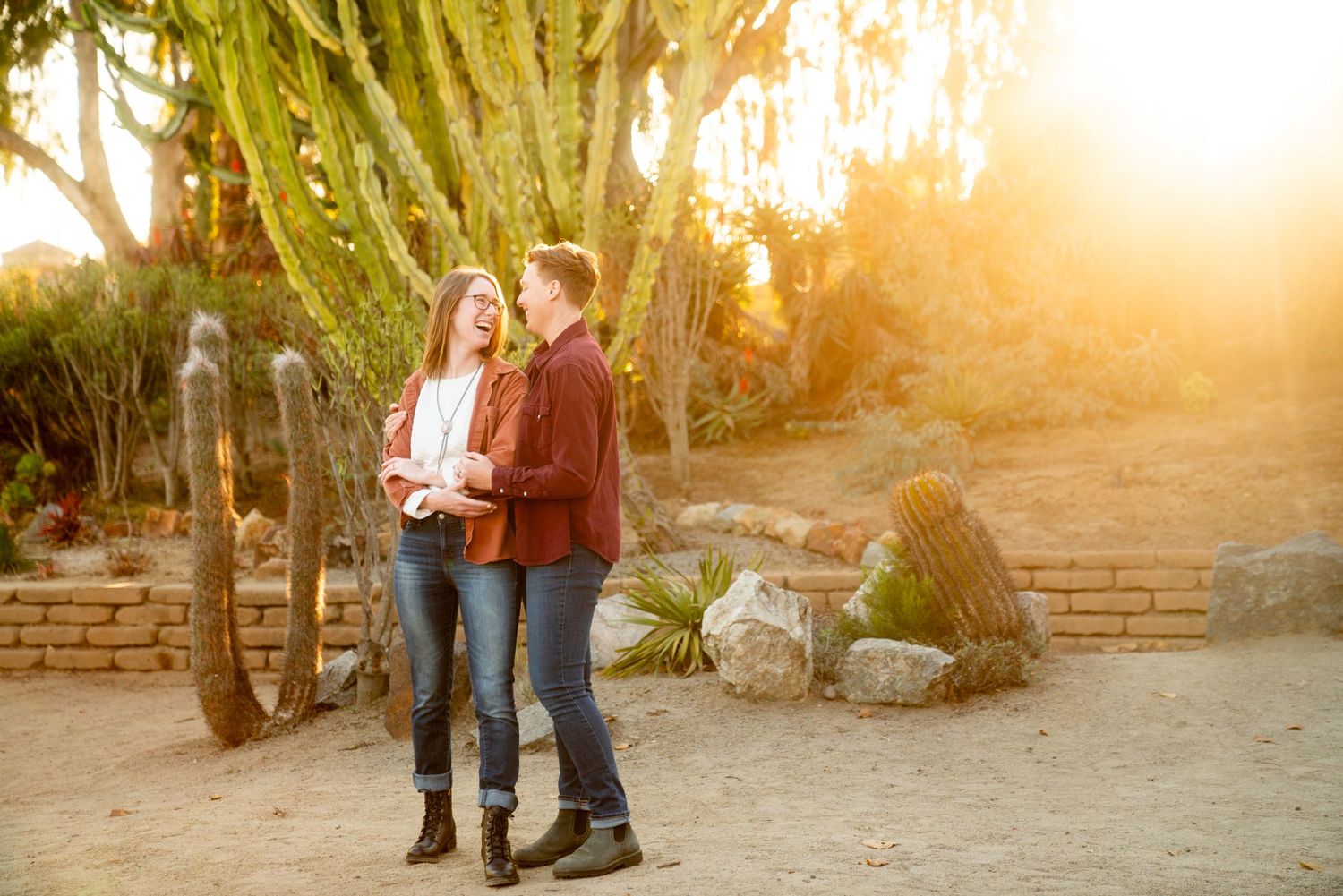 Couple posing together in desert garden setting with warm sunset lighting.