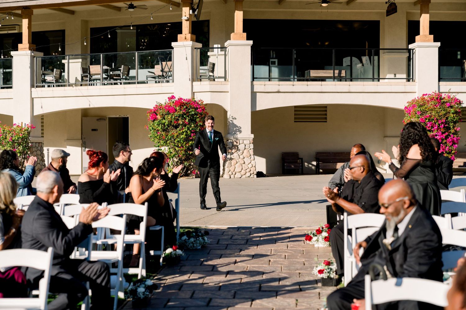 Wedding ceremony setup with white chairs and floral decorations on outdoor terrace.