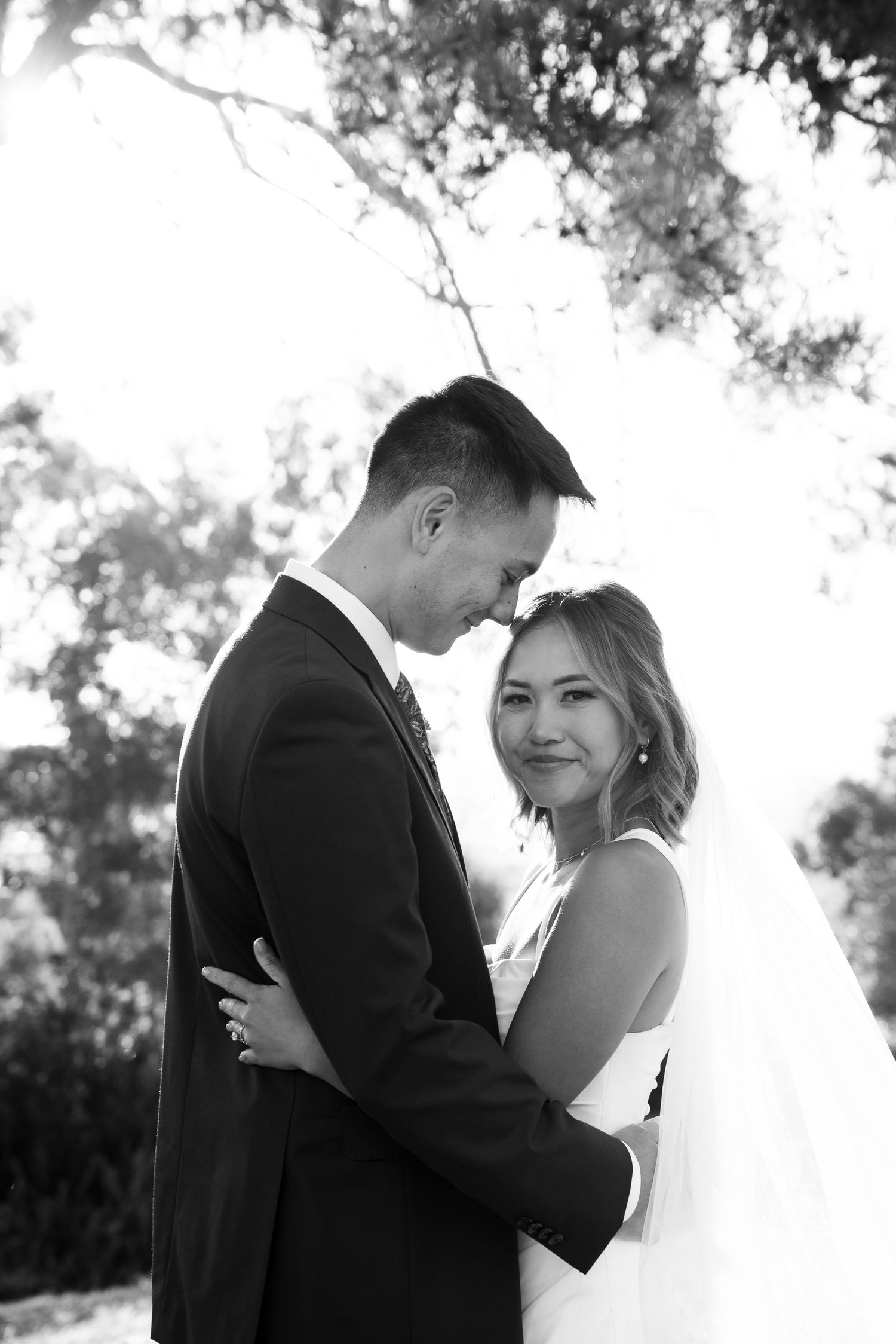 Black and white portrait of newlyweds embracing outdoors in an intimate moment.