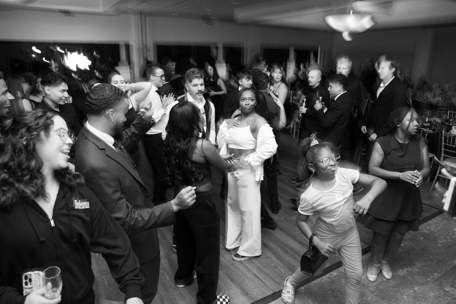 Black and white photo of wedding guests dancing and celebrating on the dance floor.