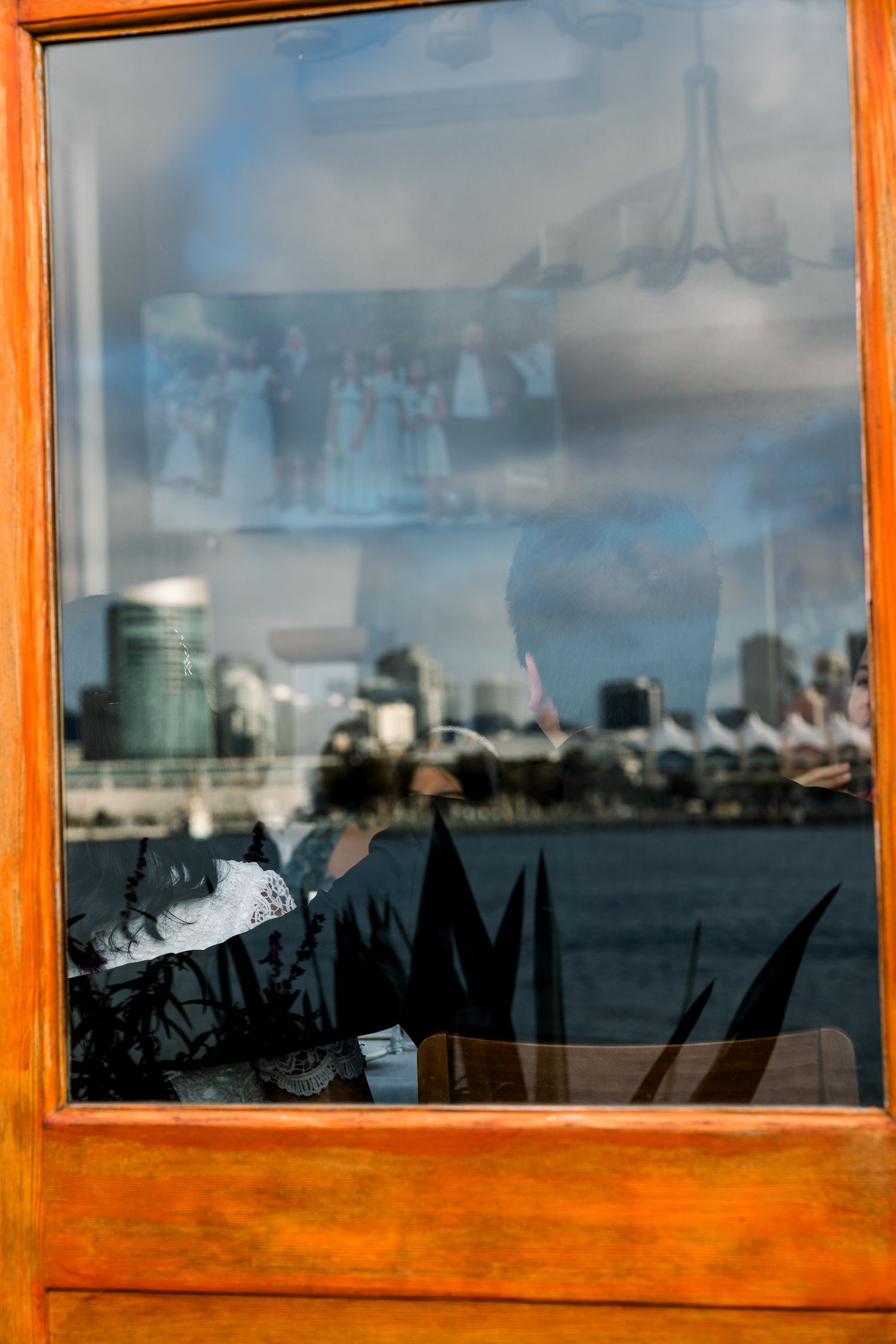 City skyline reflection in window with orange wooden frame and blurred details.