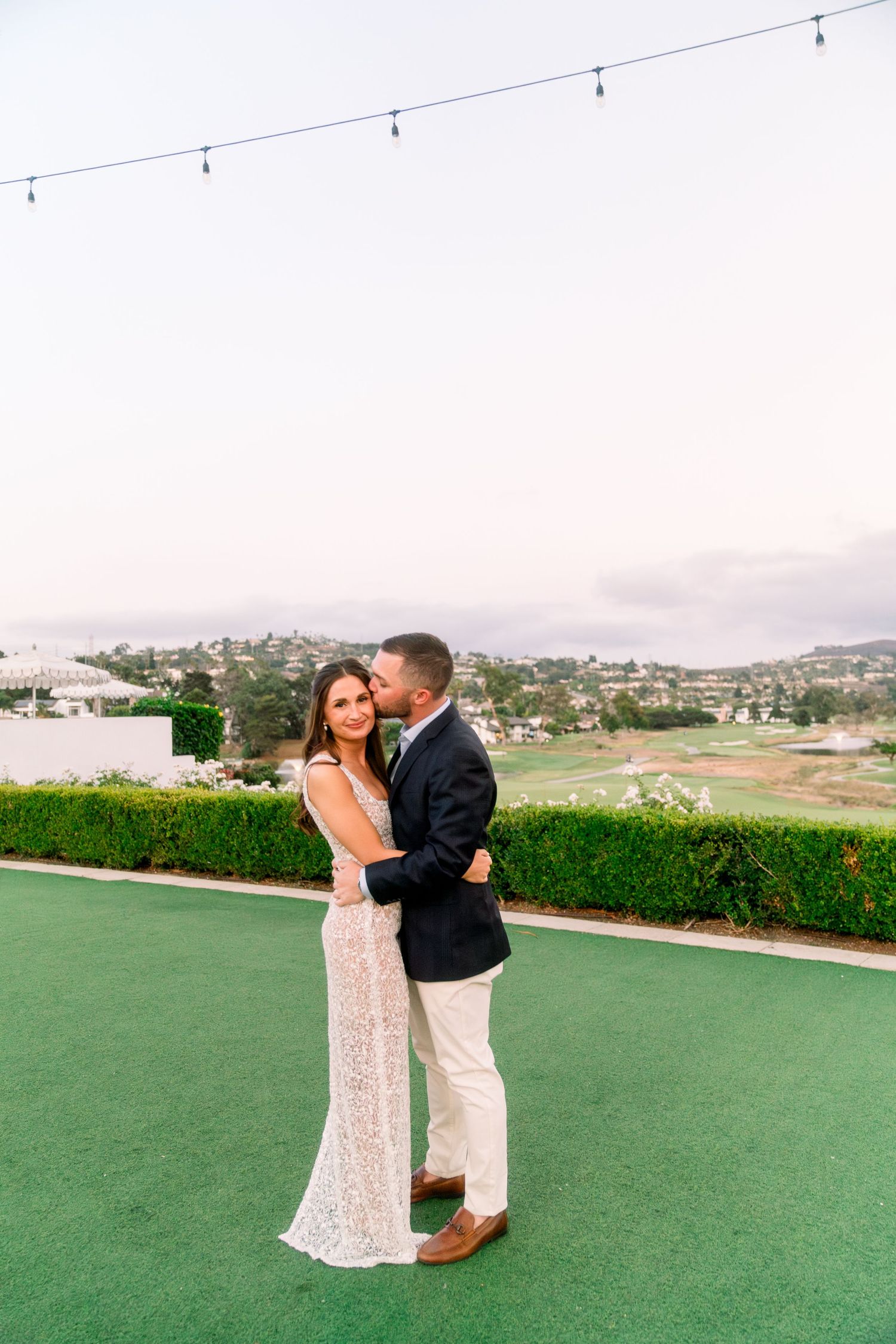 A romantic moment on a green terrace overlooking a scenic landscape.