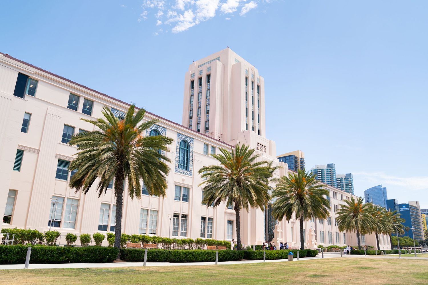 White art deco building with palm trees and tower in San Diego's downtown area on a sunny day.