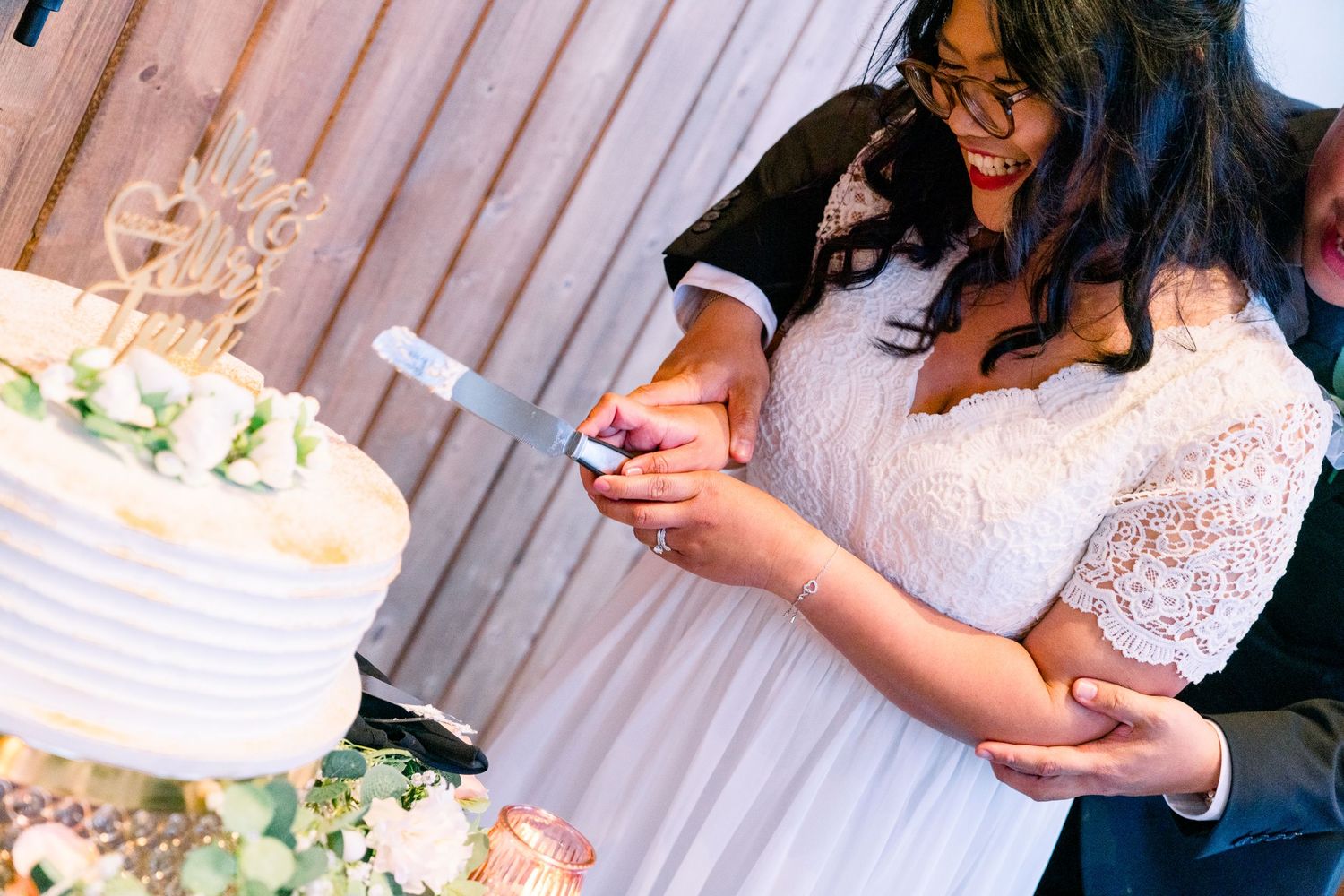 Close up of wedding cake being cut with white textured frosting and floral decorations.