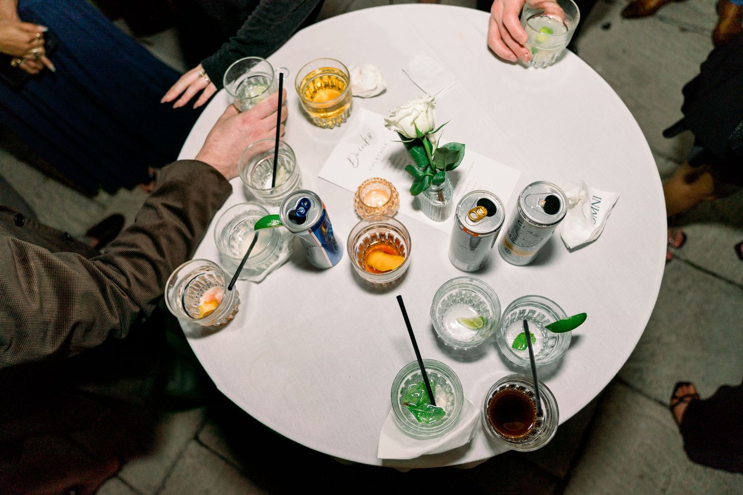 Overhead view of cocktails and drinks on a round white table.
