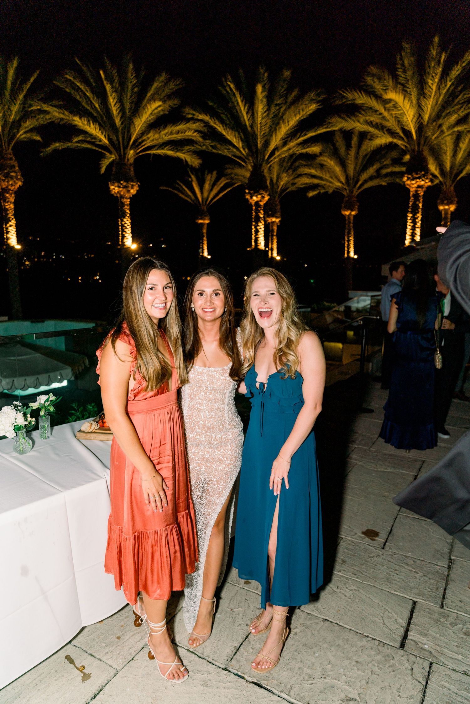 Evening celebration by illuminated palm trees on an elegant outdoor terrace.