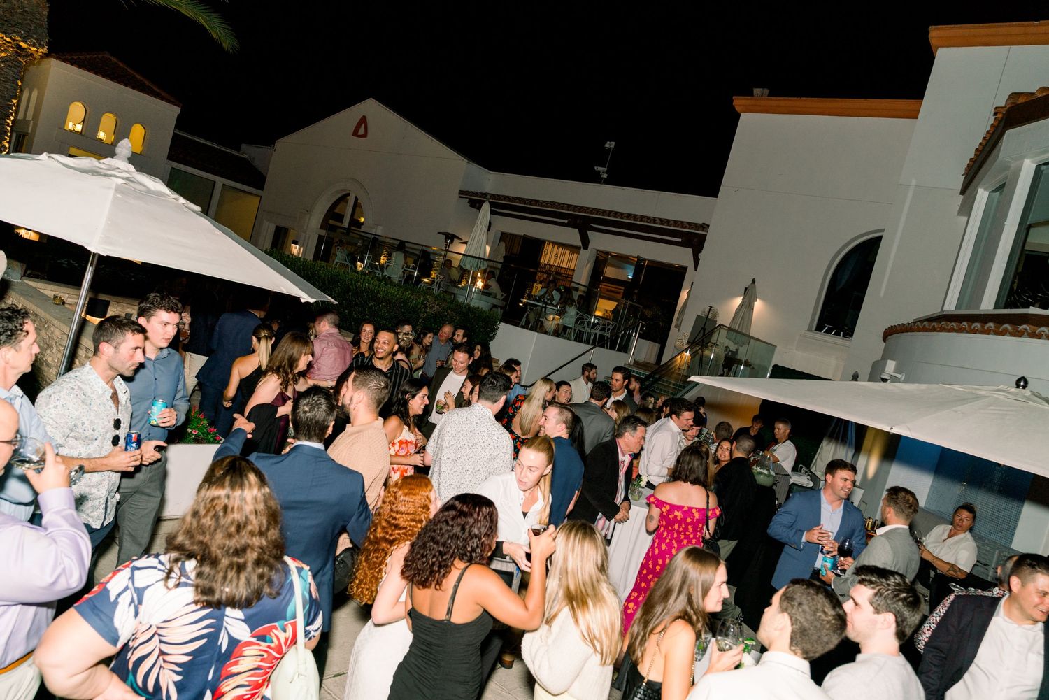 A crowded outdoor party at night with people dancing and socializing on a patio.