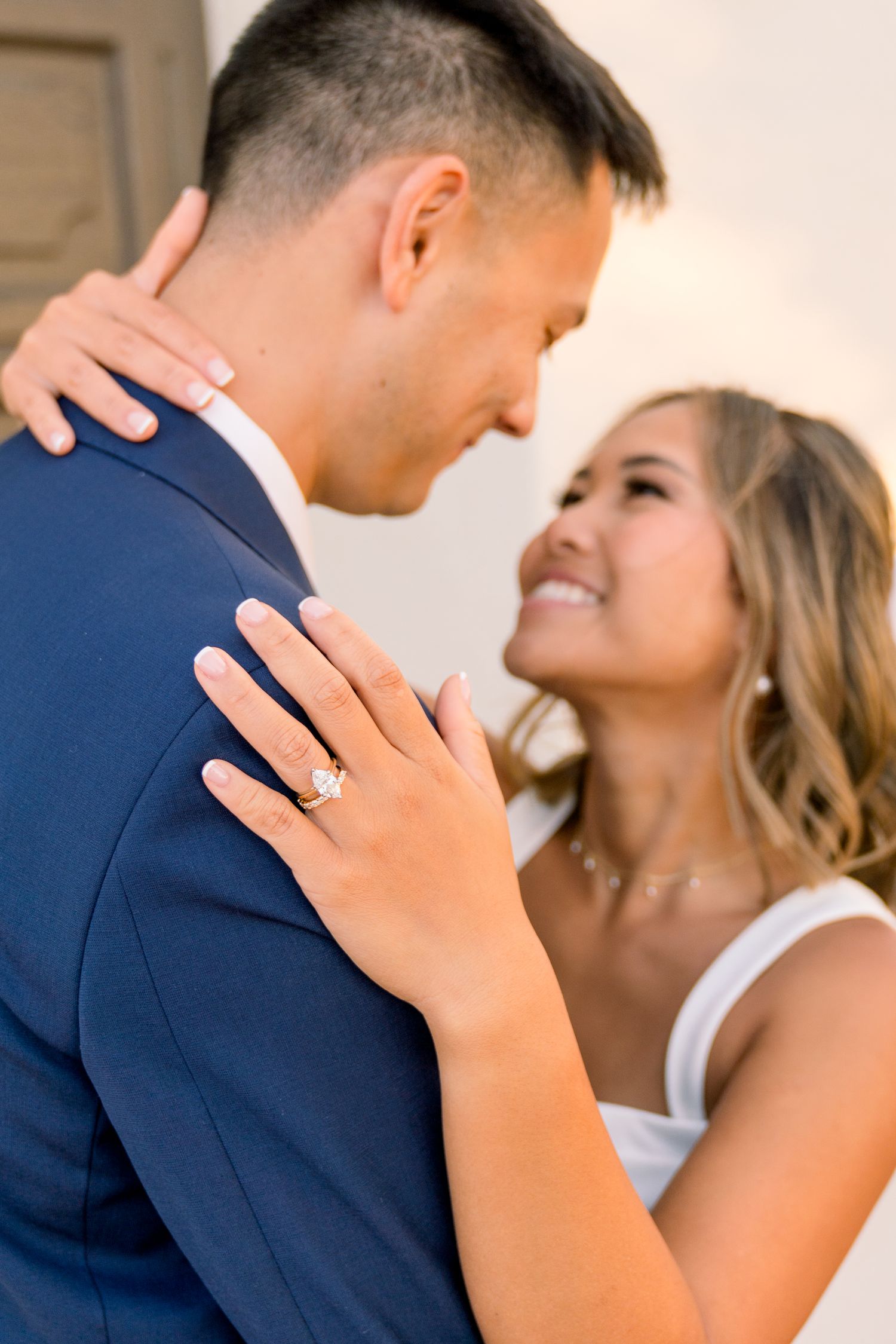 A romantic portrait of a couple embracing, with the woman's diamond engagement ring prominently displayed.