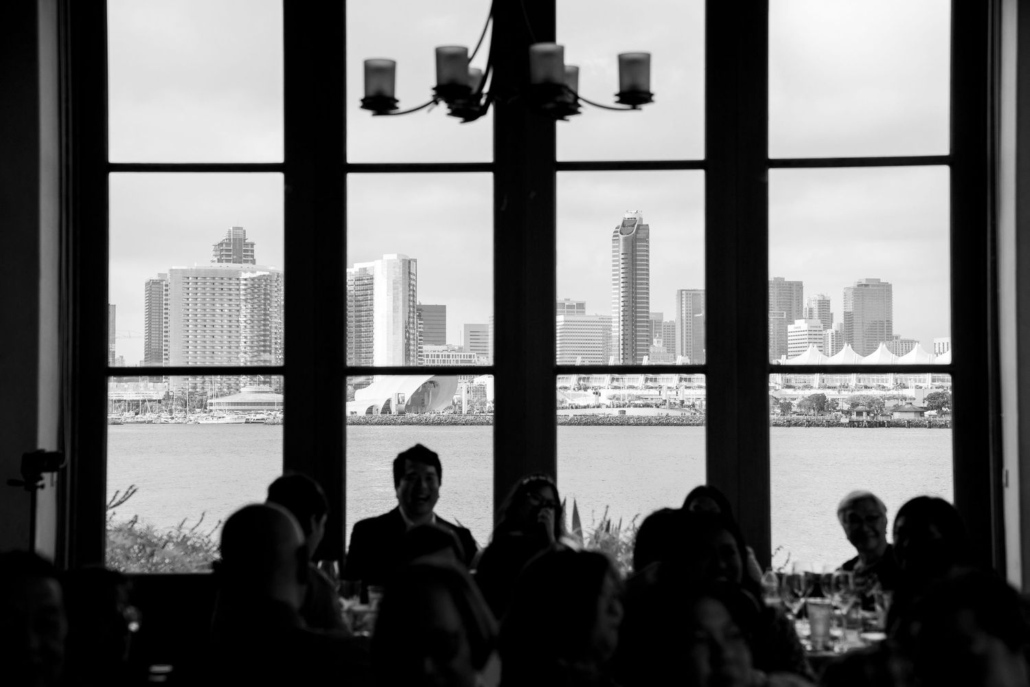 Silhouetted figures against window overlooking city skyline with dramatic lighting.