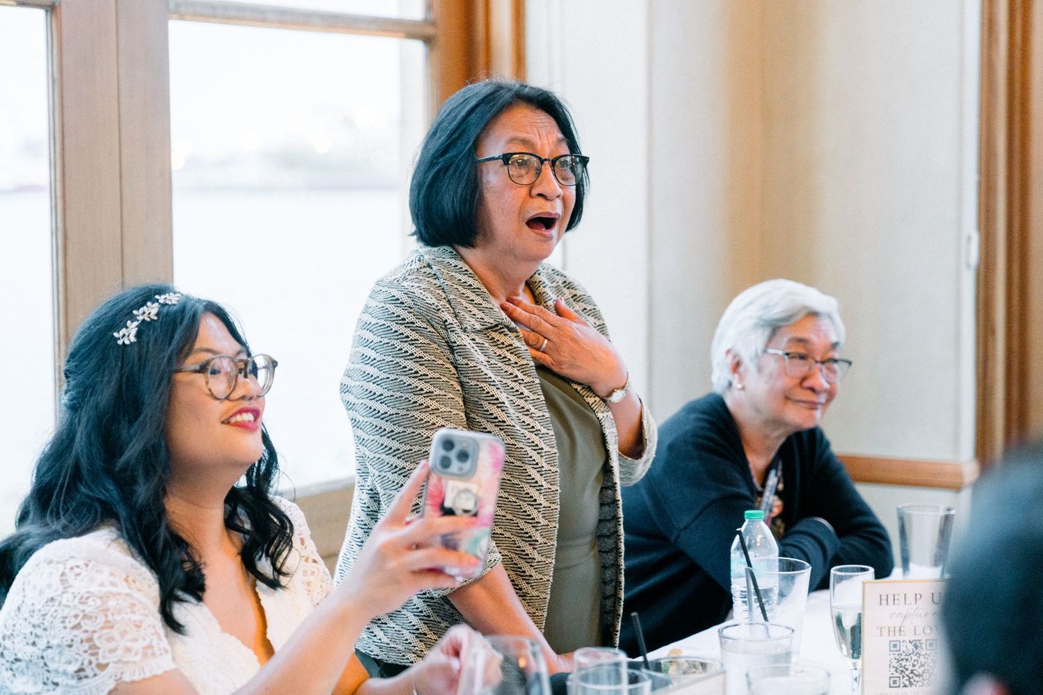 A group of friends laugh together during a social gathering at a well-lit indoor venue.