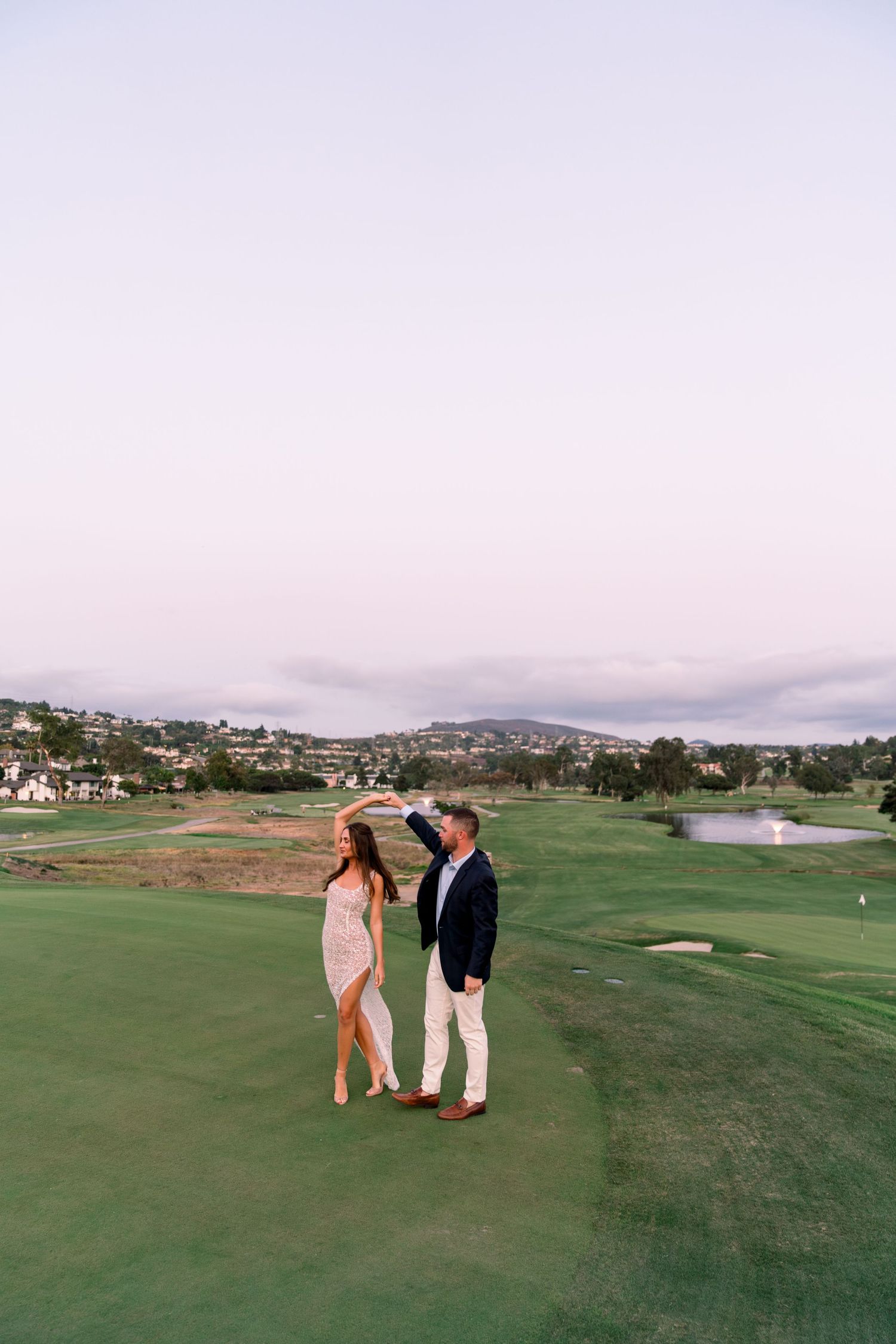A couple sharing a romantic moment on a scenic golf course at sunset.