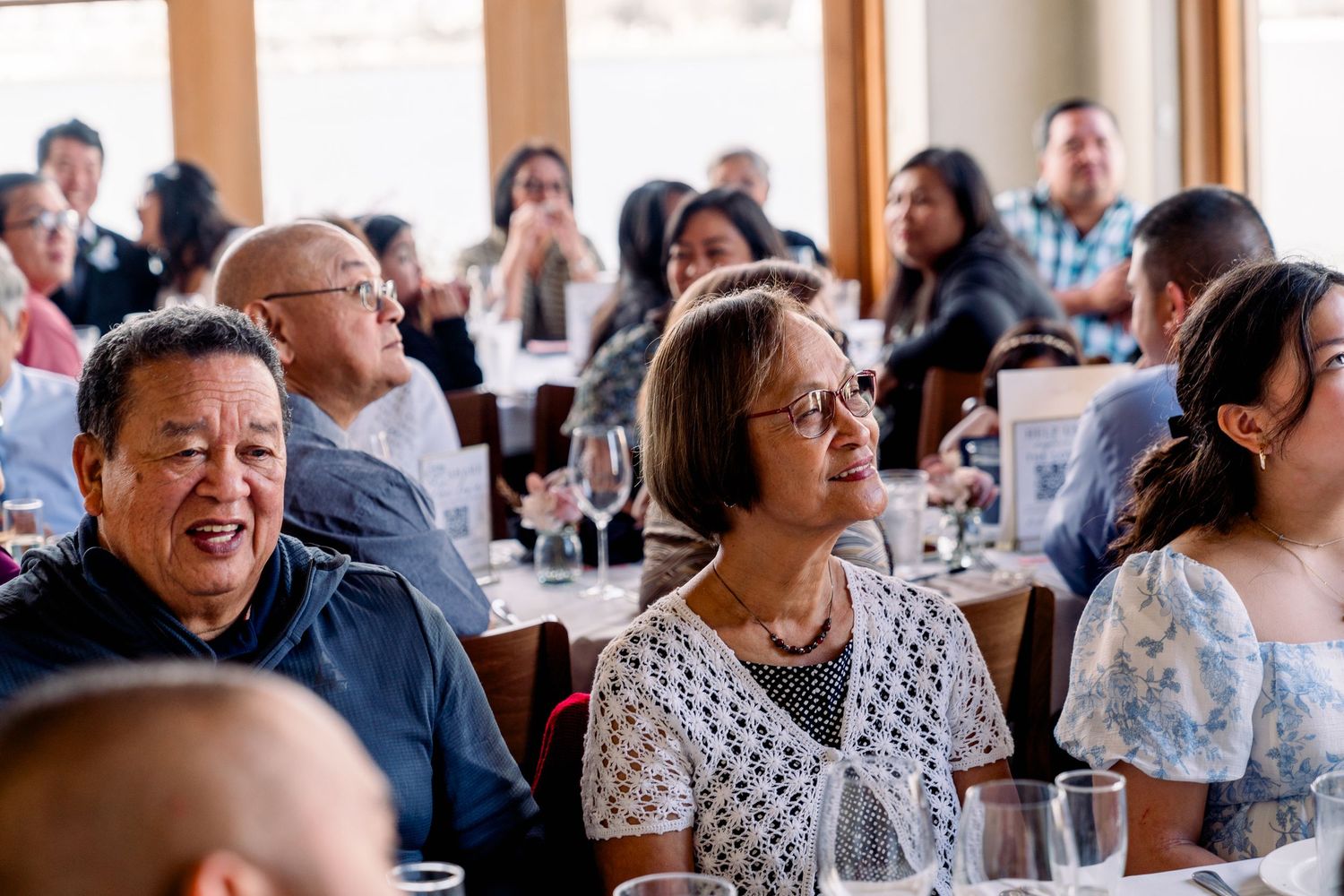 Wedding guests enjoying reception celebration in sunlit dining room.