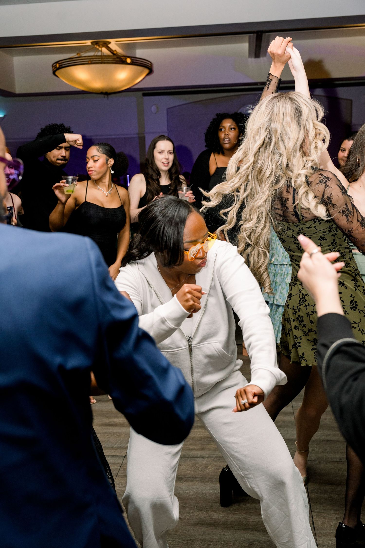 Wedding guests dancing and celebrating energetically on the dance floor at a reception.