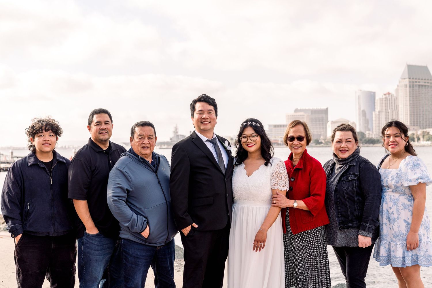A group of people stands together posing outdoors against a city skyline backdrop with tall buildings.