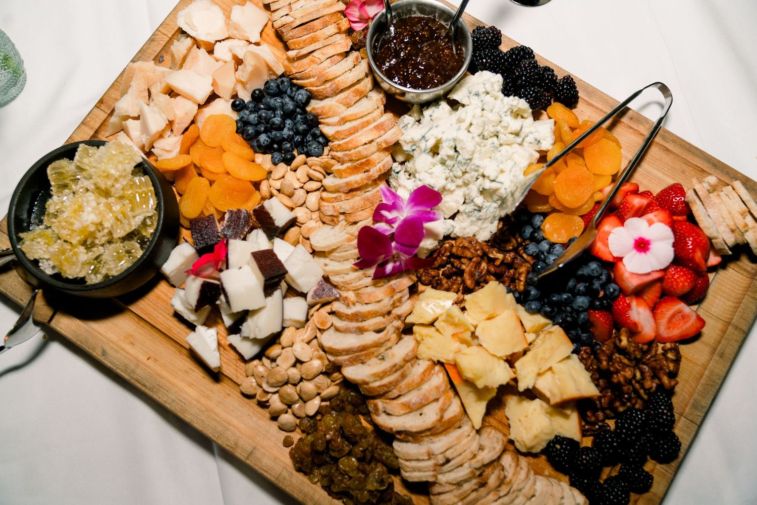 An elegant charcuterie board with fruits, cheeses, and crackers arranged on a wooden platter.