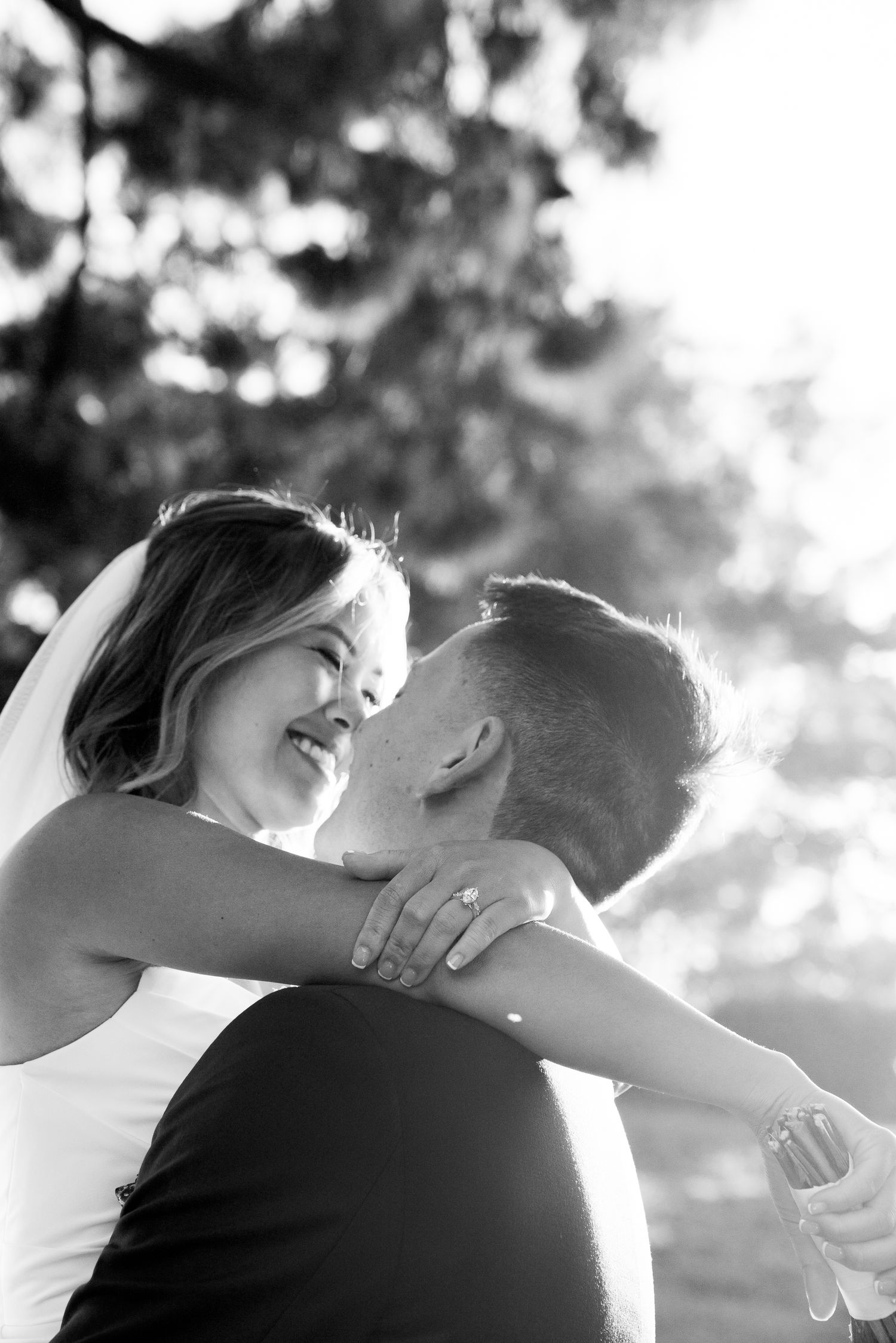 A black and white portrait captures a tender moment between newlyweds in natural lighting.