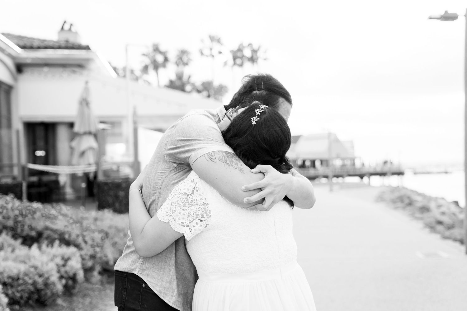 Black and white photo of a couple embracing outdoors in wedding attire.
