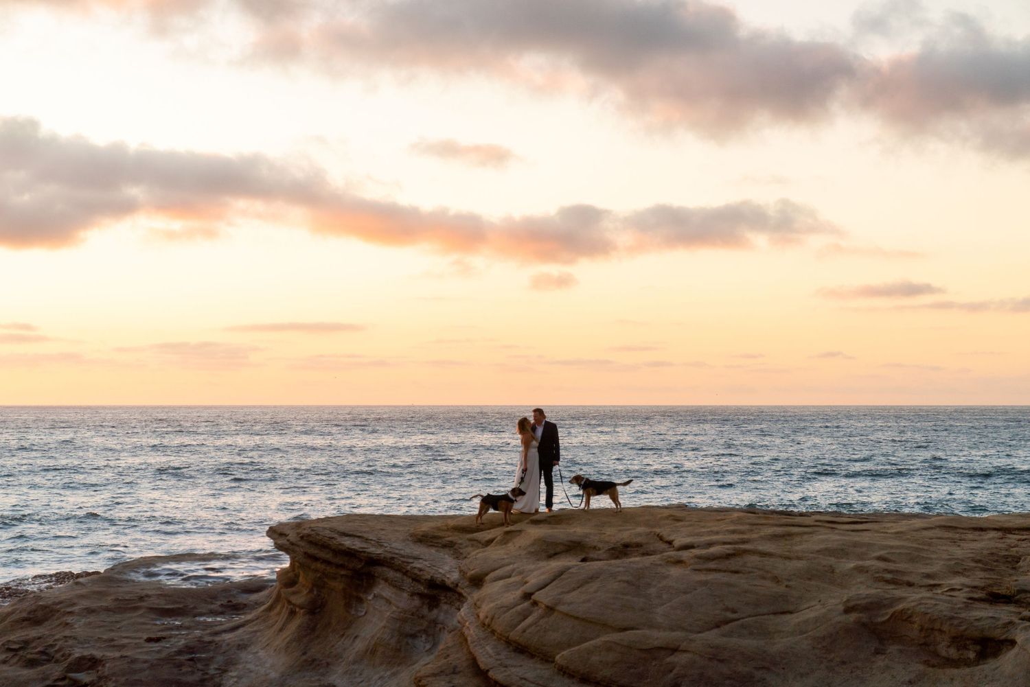 Silhouette of figures against dramatic sunset sky at ocean overlook.