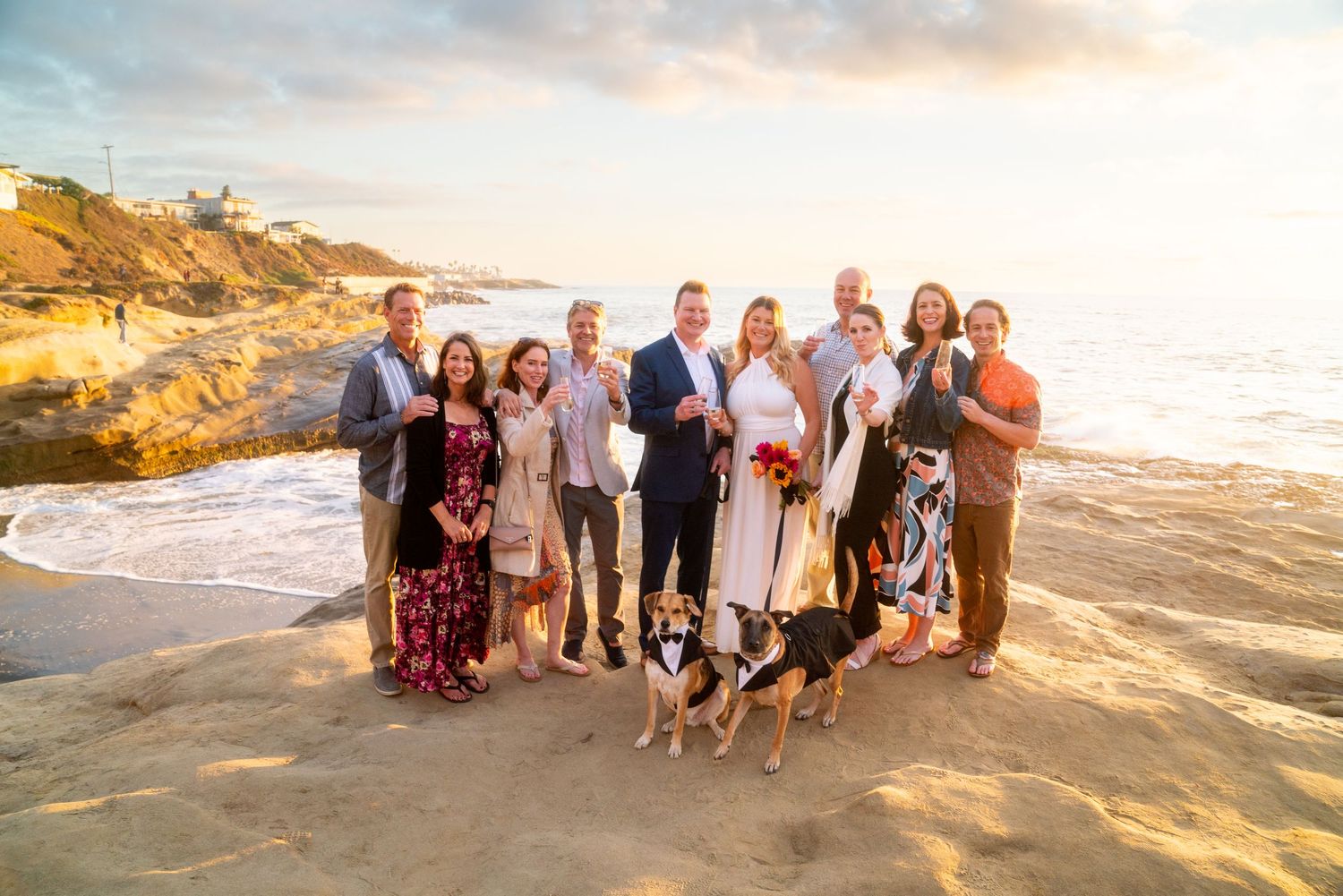A group poses together on a sandy beach at sunset, creating a warm and scenic family portrait moment.