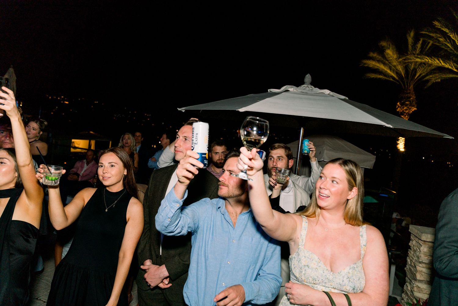 Guests raise their drinks in celebration during an outdoor nighttime party.