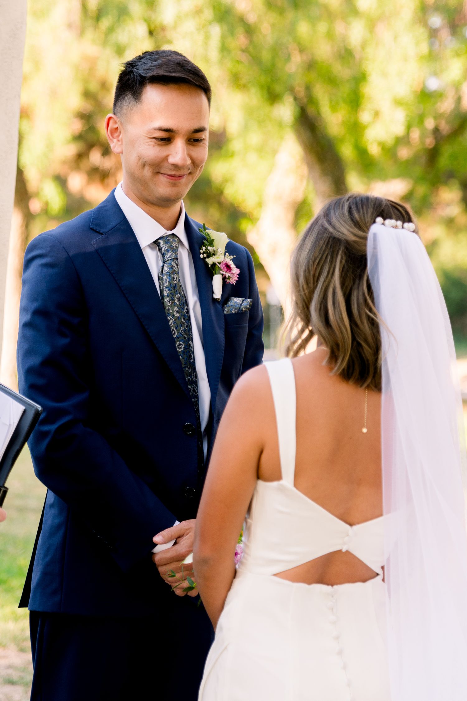A bride and groom share an intimate moment during their outdoor wedding ceremony with soft natural lighting.