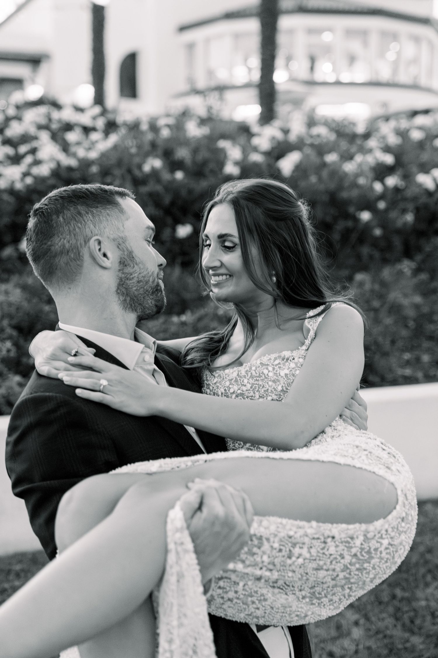 A romantic black and white portrait of a couple embracing outdoors.