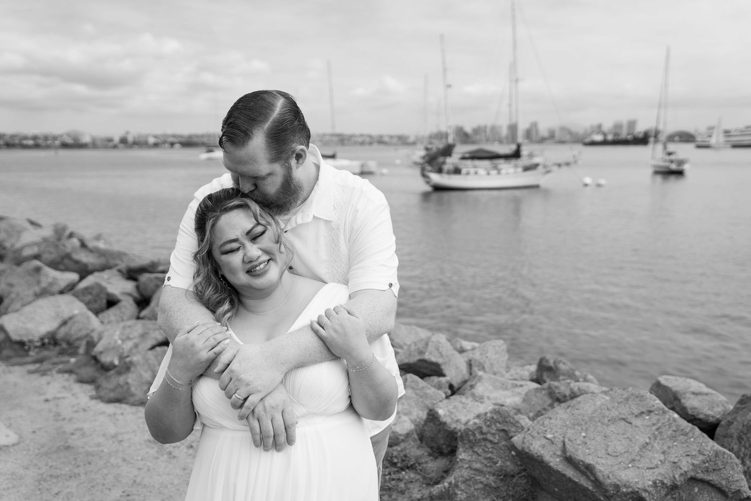 An engagement photoshoot at the harbor shows intimate moments of a couple posing along the waterfront.