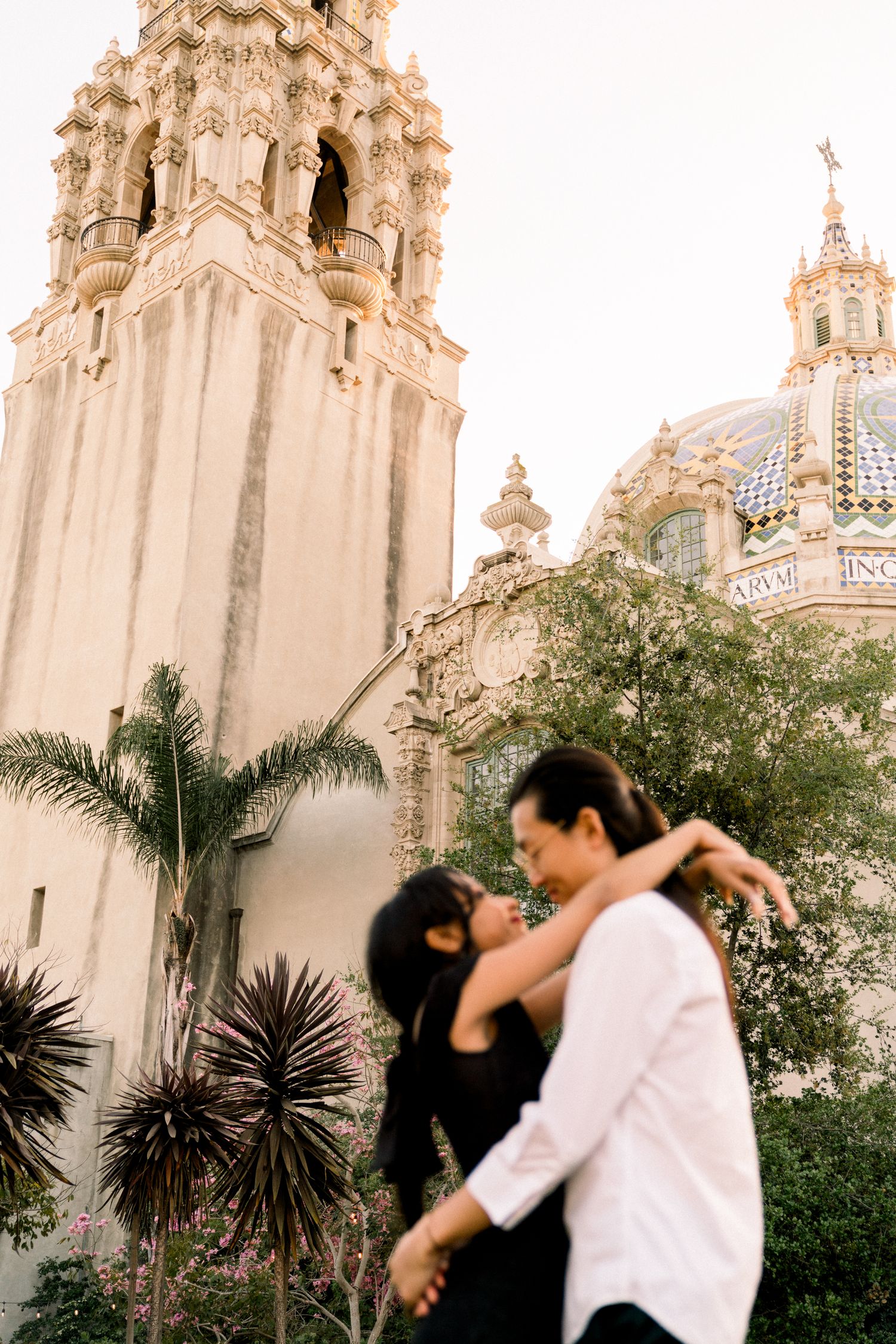 An elegant Spanish colonial style church tower with ornate architectural details and palm trees.