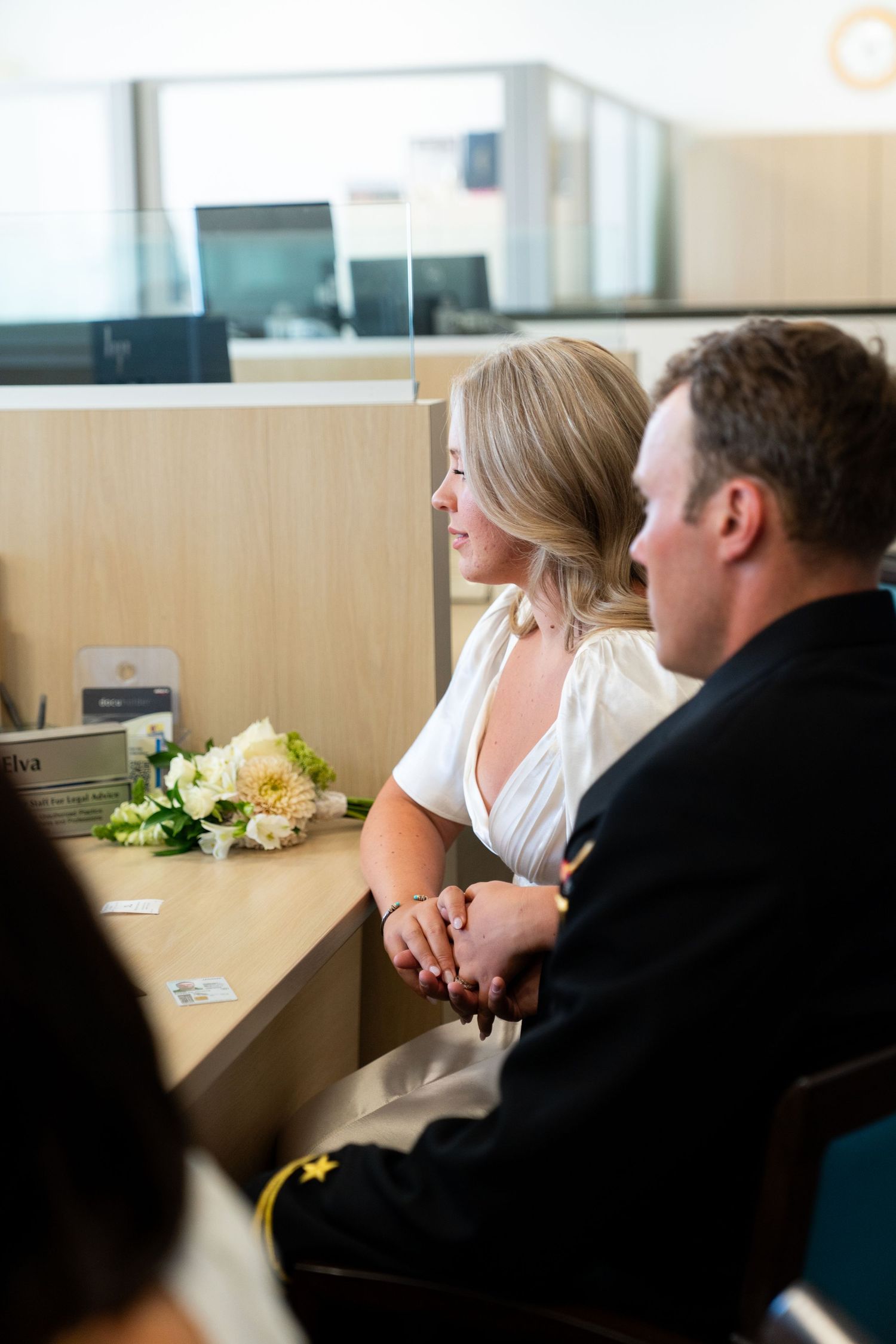 A couple sits together at a desk with yellow flowers while having a meeting or consultation in an office setting.