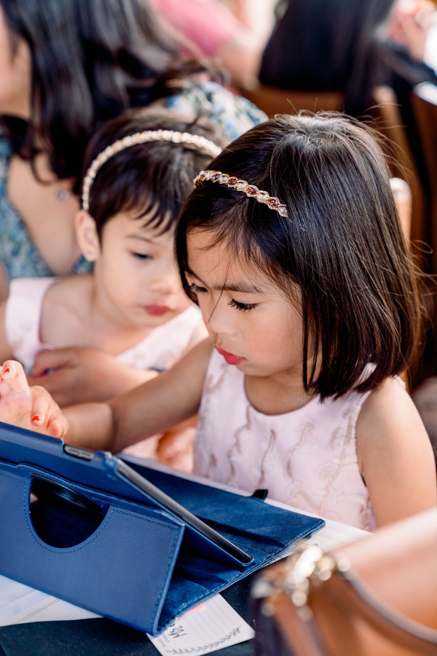 Young children in formal attire looking at items during a wedding reception.