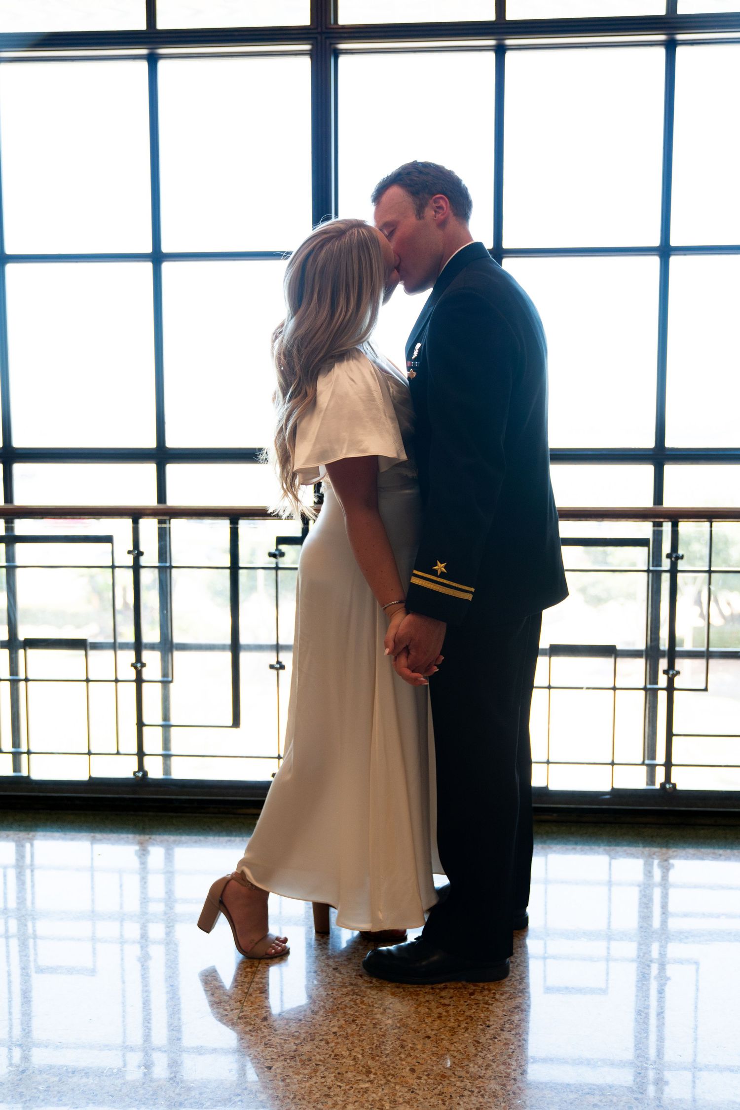 Three duplicate views of a couple in formal attire standing in a bright room with large windows and reflective floors.