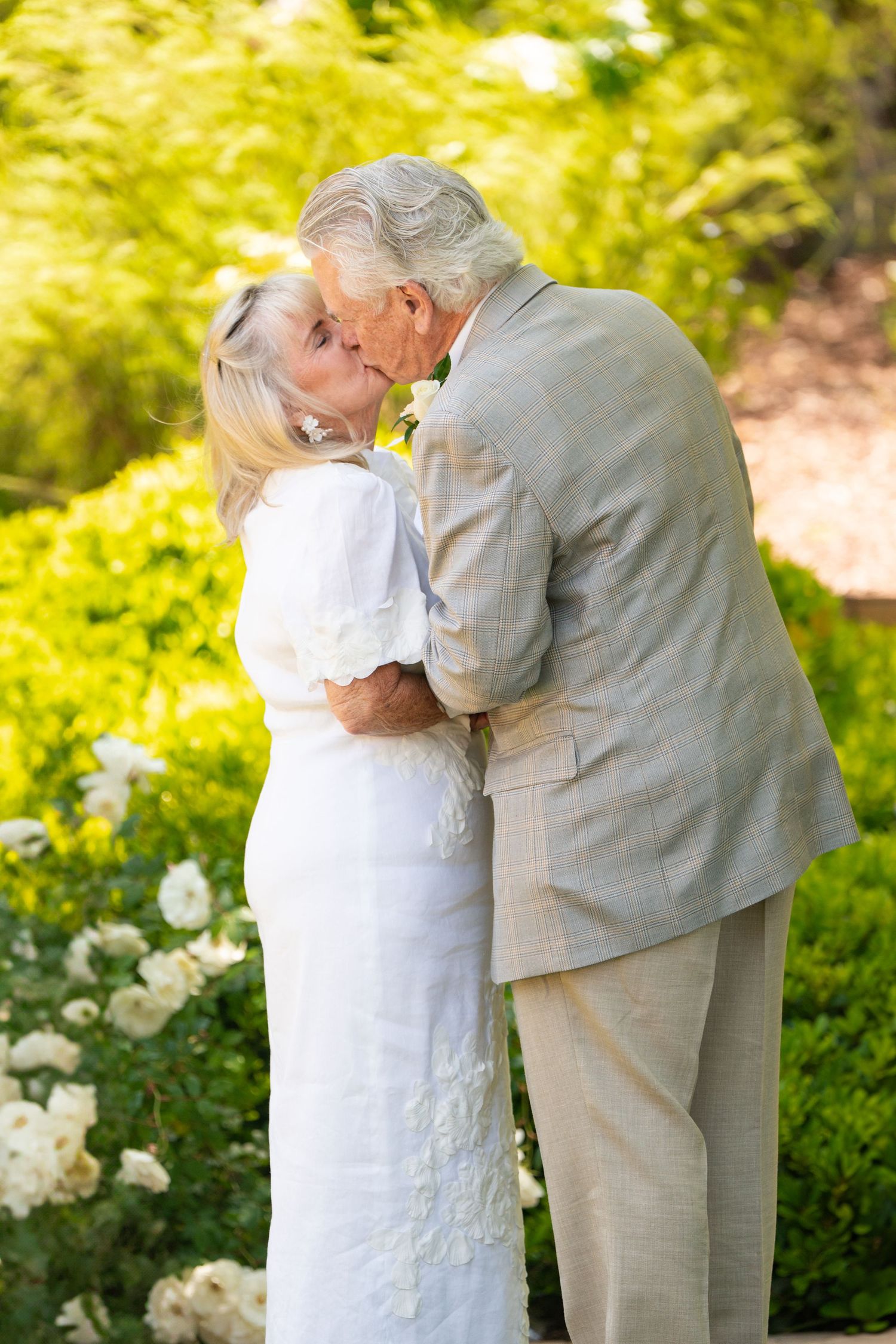 A tender moment between a couple in formal attire during their garden wedding.