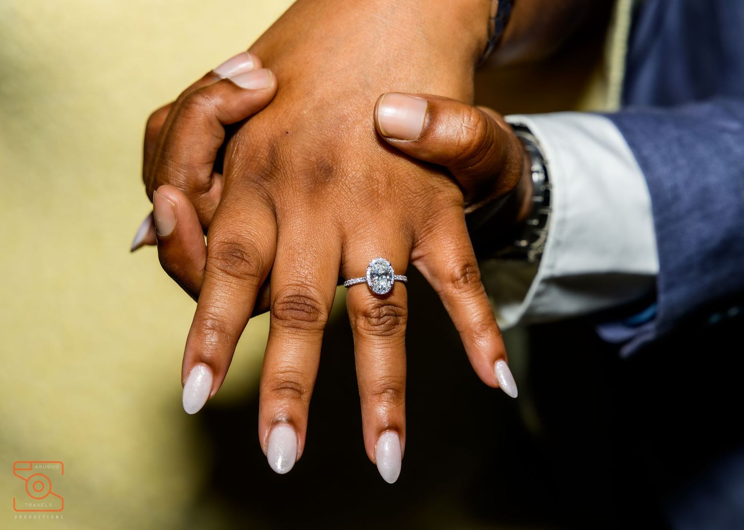 Close-up of hands with engagement ring showing French manicured nails and wedding jewelry.
