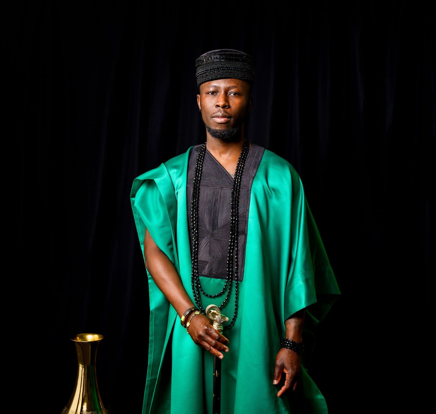 Traditional green ceremonial robe photographed against dark background with gold accents.